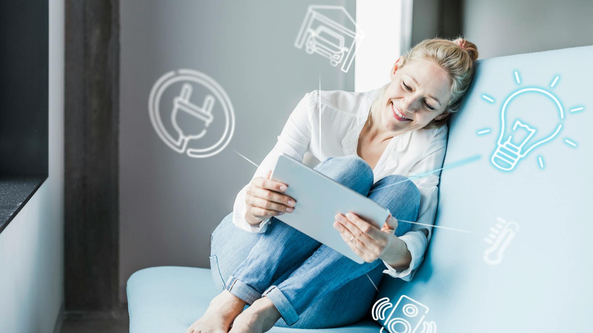 Frau sitzt auf dem Sofa und hält ein Tablet in den Händen.