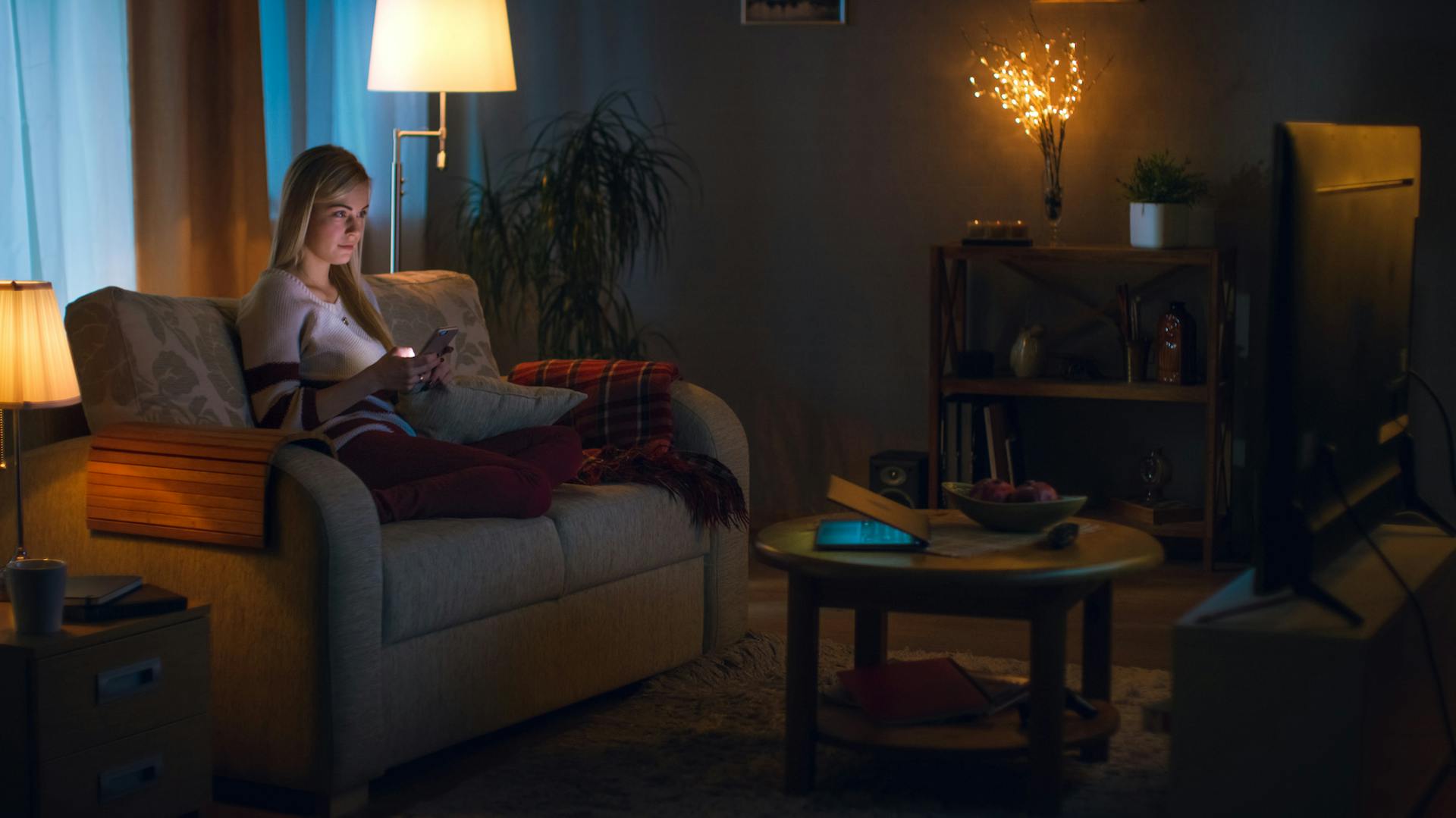 Frau mit Smartphone steuert Beleuchtung per App