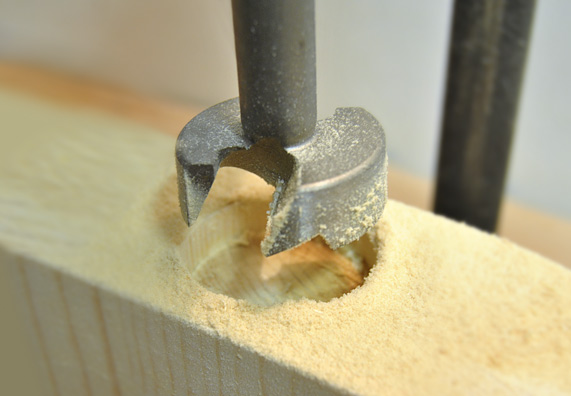 Vertiefung wird in einen Balken gebohrt.