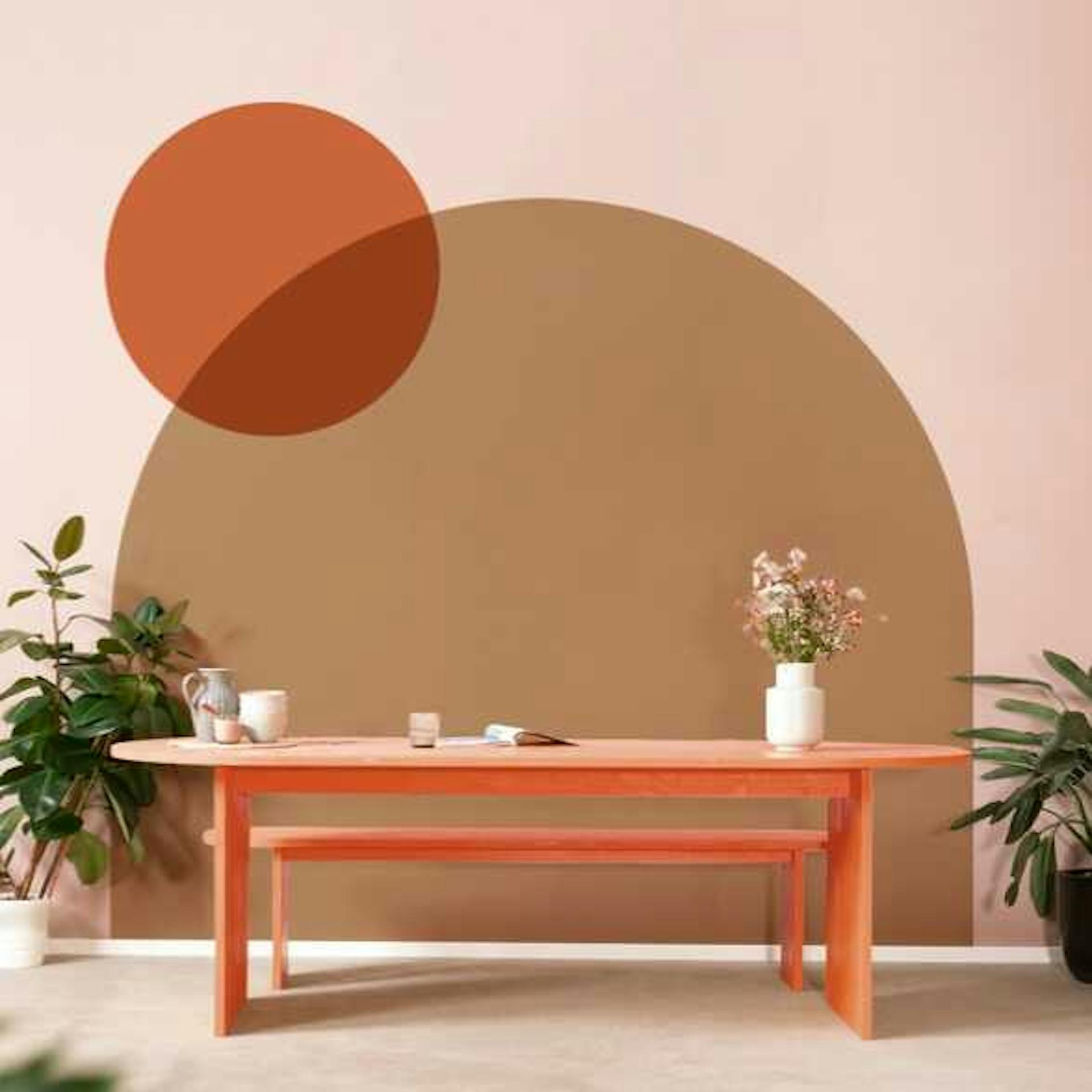 Tisch Clemens steht zentriert vor einer Wand, die verschiedene Farbflächen in warmen Erdtönen als Wandgestaltung nutzt.