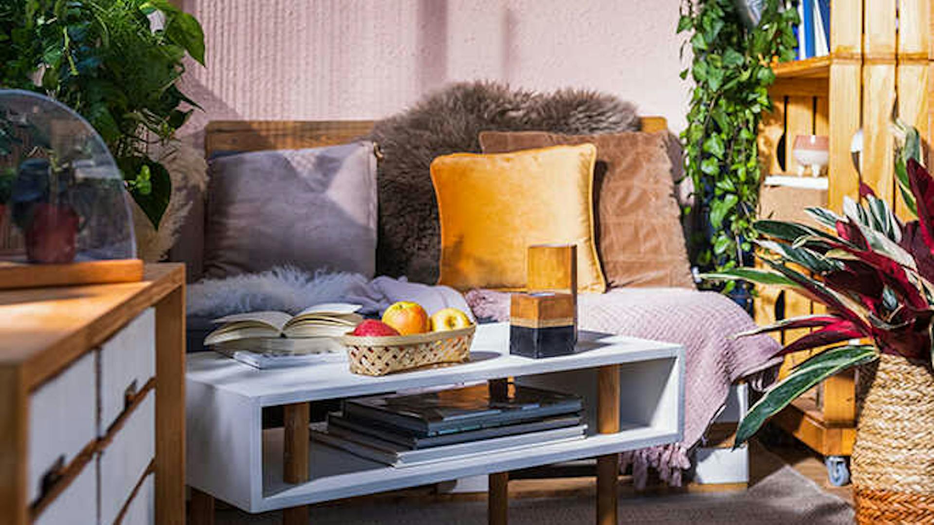 Couchtisch Vera steht vor einer mit Kissen und Decken dekorierten Palettencouch Bankig auf einem gemütlichen Balkon.
