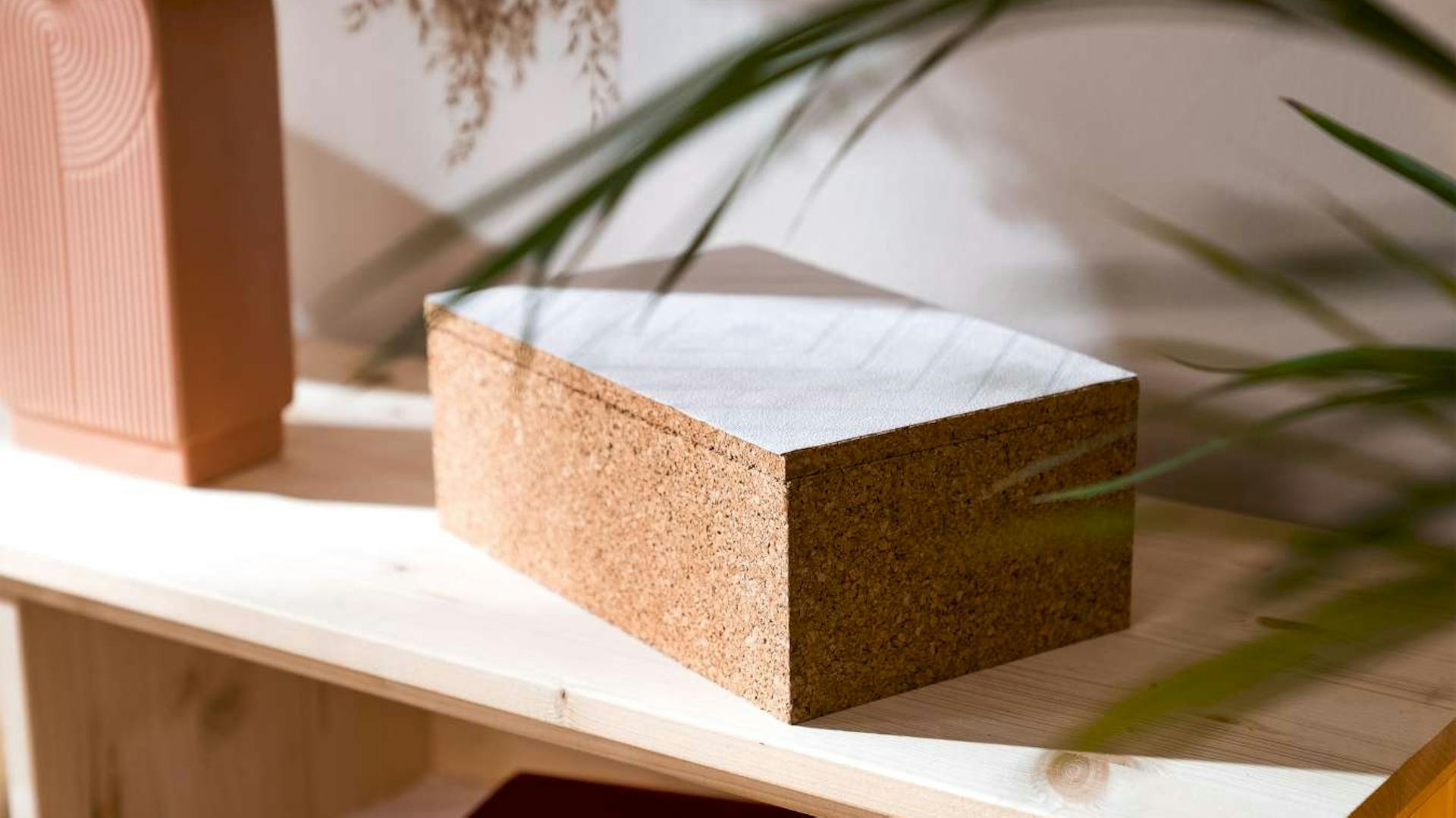 Eine Korkbox liegt auf einem Regal neben einer Vase.