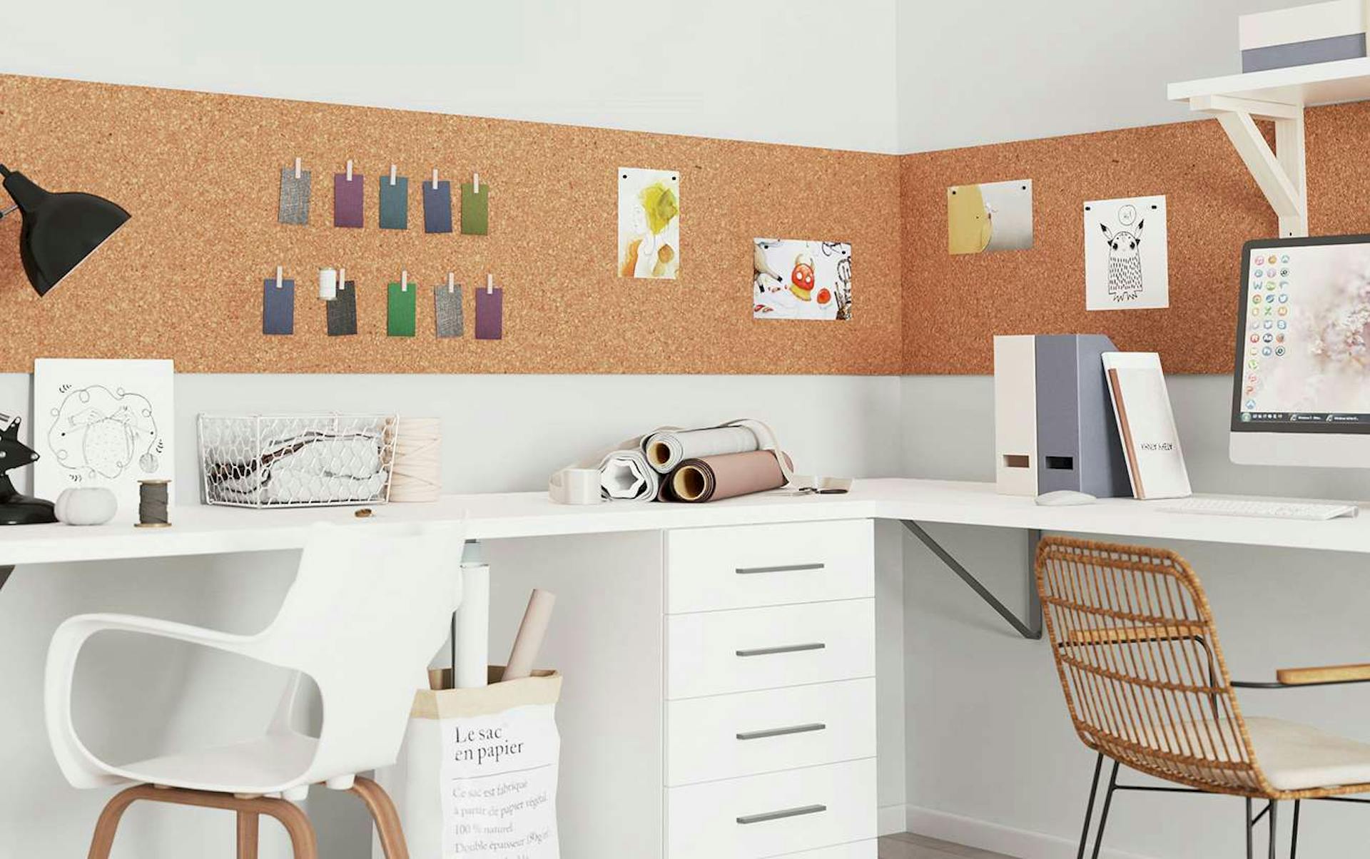 Über zwei aneinandergestellten Schreibtischen hängt eine Korkwand.