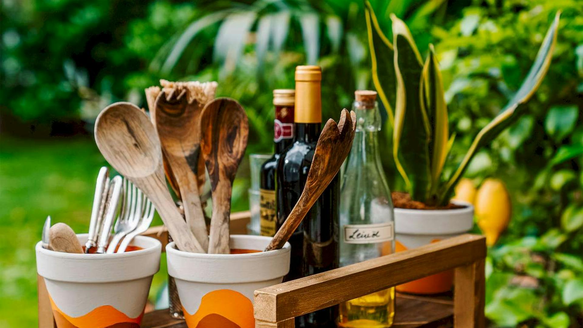 Bemalte Terrakottatöpfe, in denen Besteck steht, stehen auf einem Servierwagen.