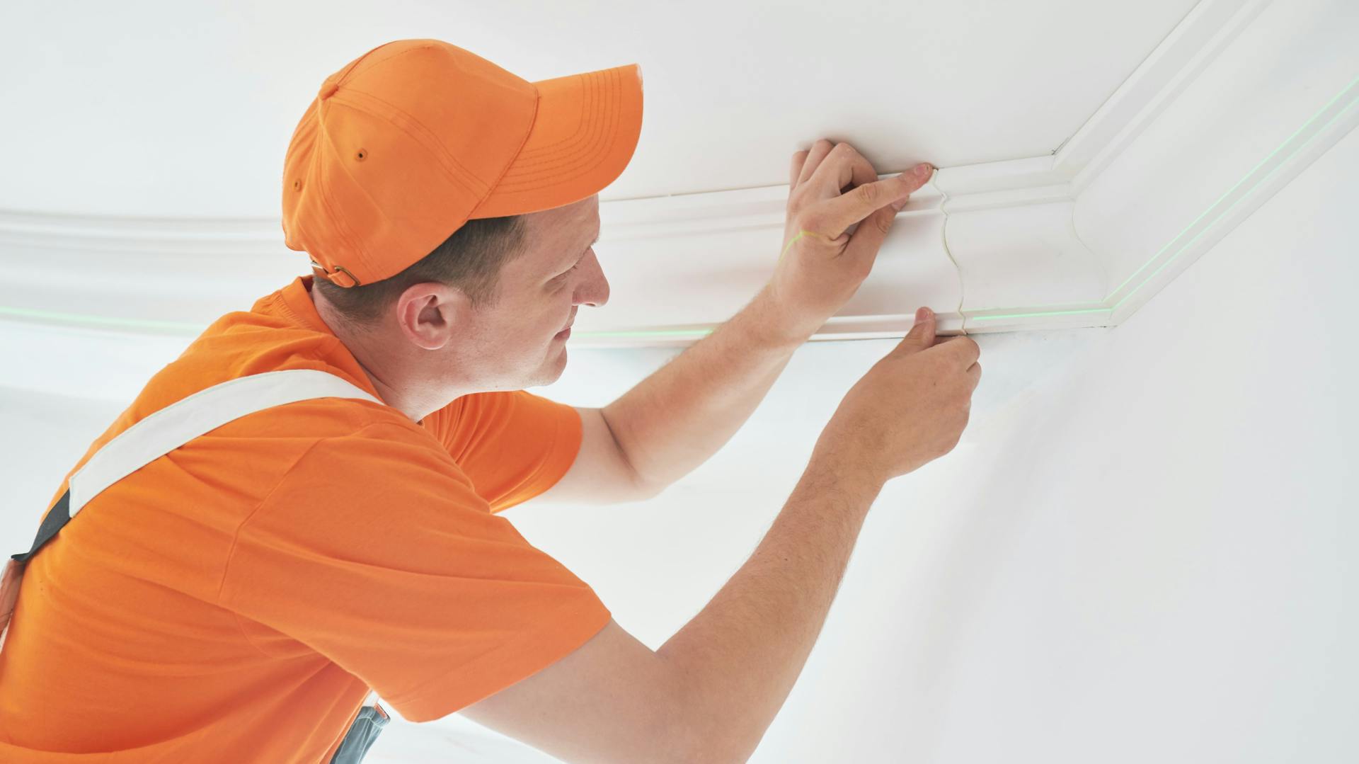 Niekto prikladá k stropu štukovú lištu.