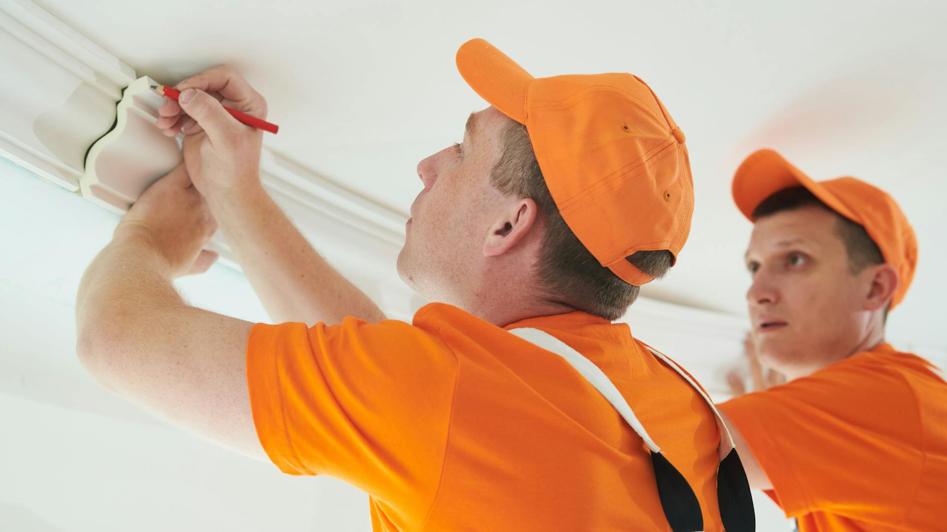 Dve osoby vymeriavajú štukové lišty