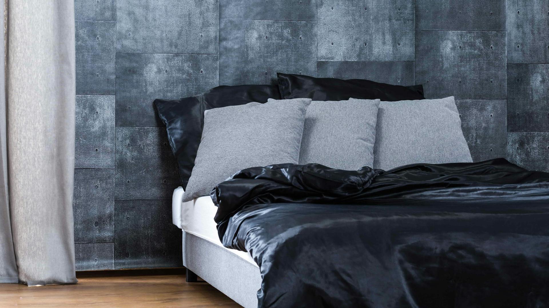 Ein Bett steht vor einer grauen Mustertapete