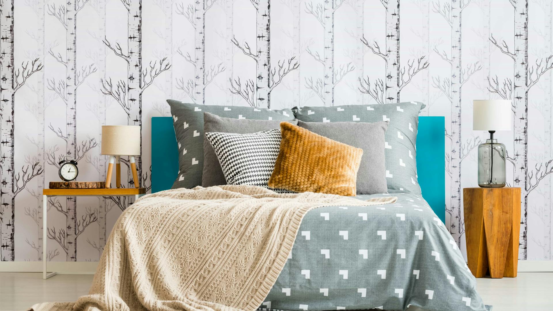 Tapete mit Baummotiven hinter einem Bett im Schlafzimmer.