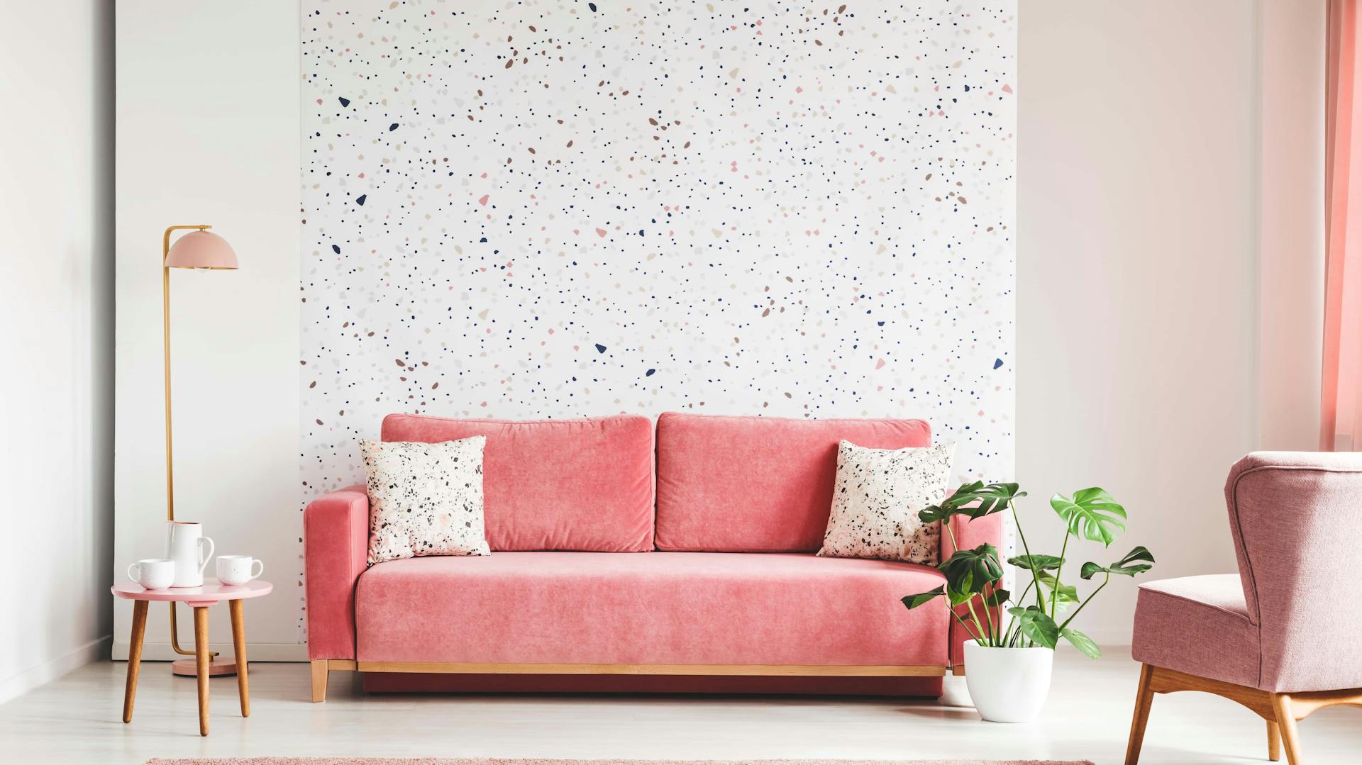 Rosa Sofa in Wohnzimmer vor rosa gepunkteter Tapete an Wand