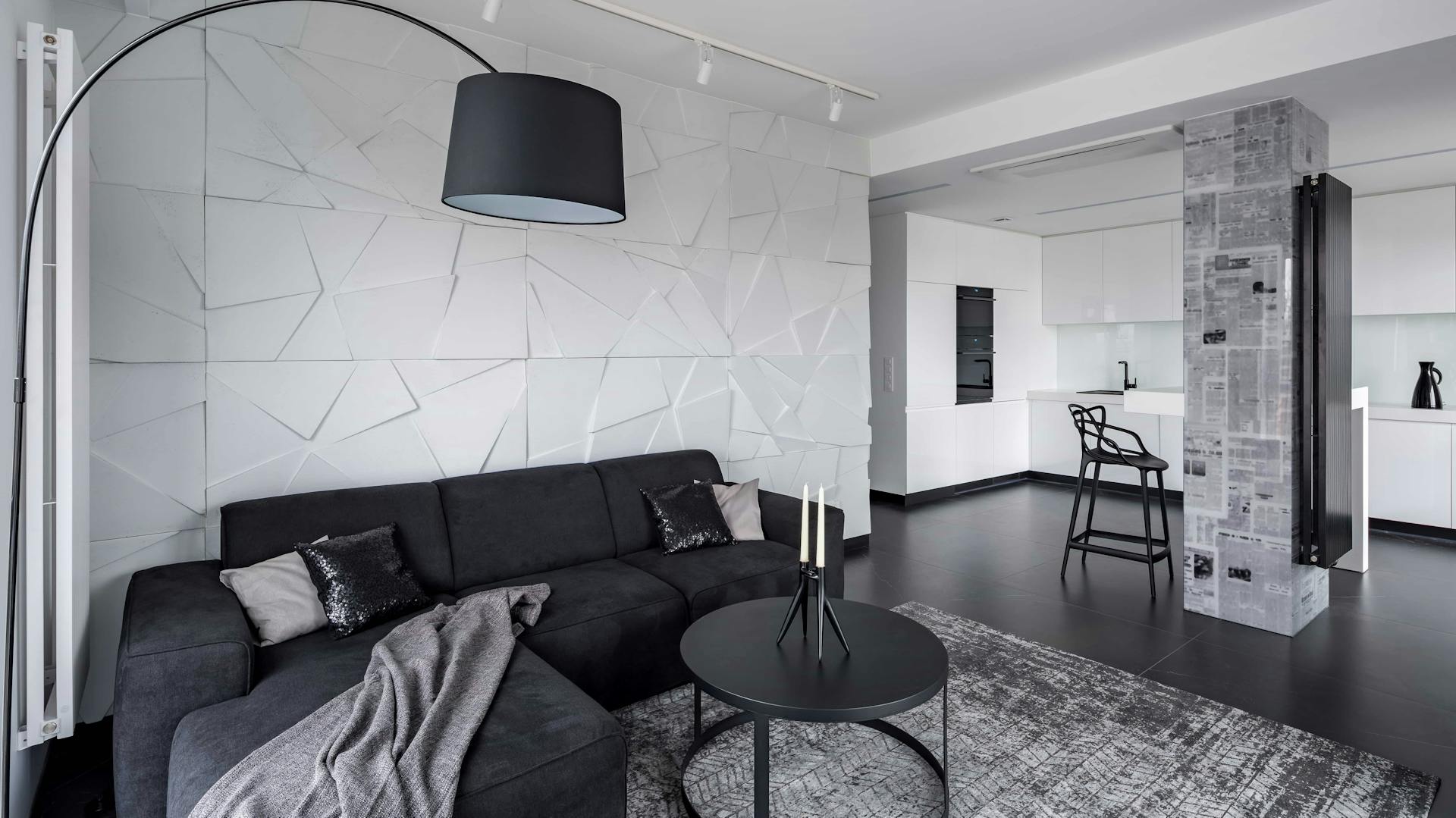 Moderne 3-D-Tapete in geometrischem Muster hinter schwarzer Couch in Wohnzimmer.