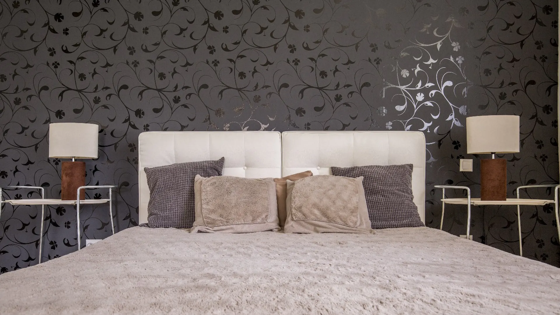 Mustertapete mit Struktur und Glanz hinter Bett im Schlafzimmer