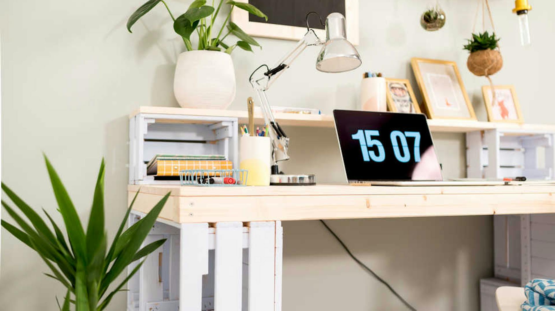 Schreibtisch aus Kisten mit Laptop, Pflanzen und Arbeitsmaterialien