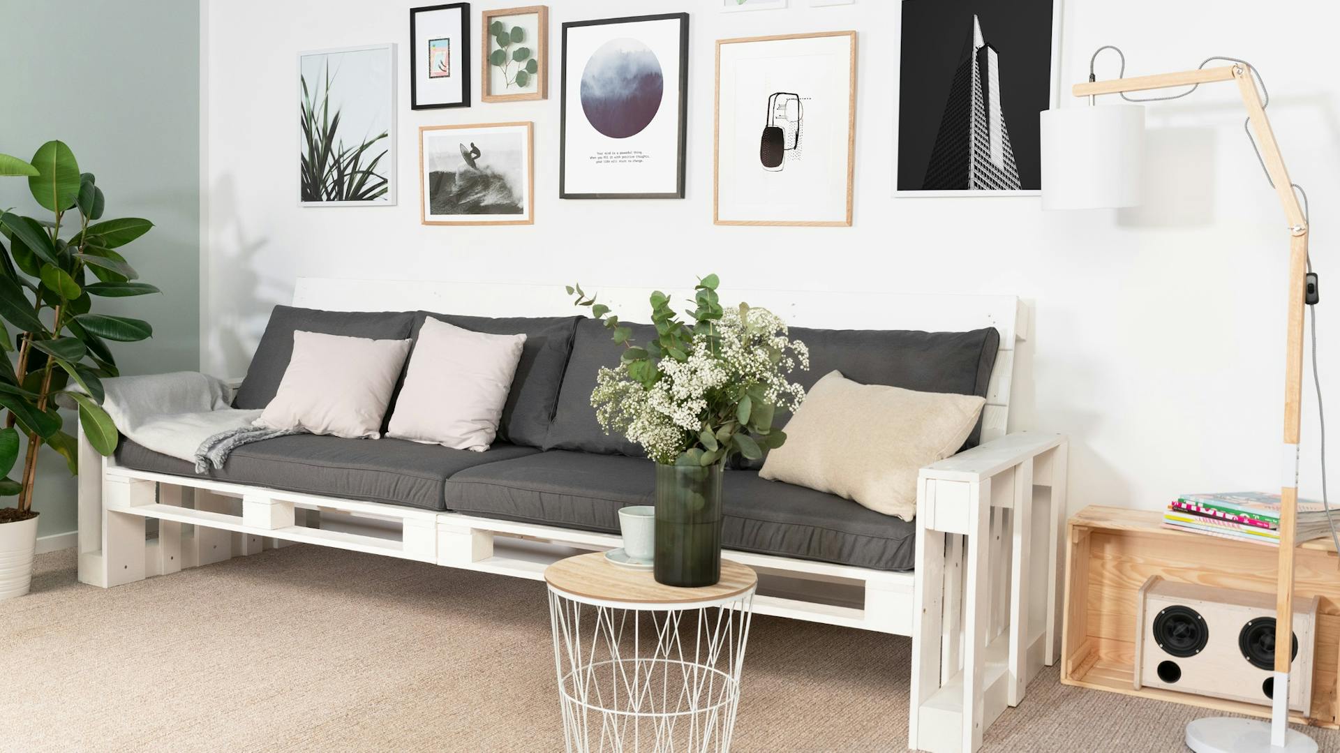 Weißes Palettensofa mit grauen Palettenkissen, Beistelltischchen und Stehlampe