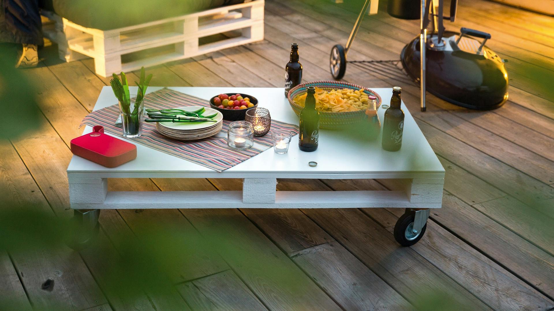 Blauer Couchtisch aus Palette mit Rollen auf Terrasse in Garten