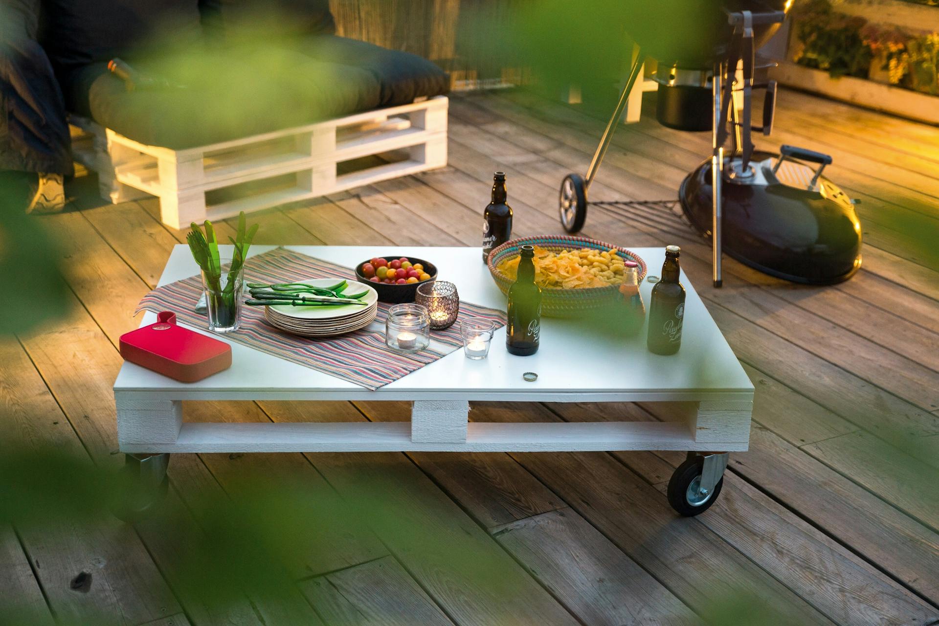 Blauer Couchtisch aus Palette mit Rollen auf Terrasse in Garten