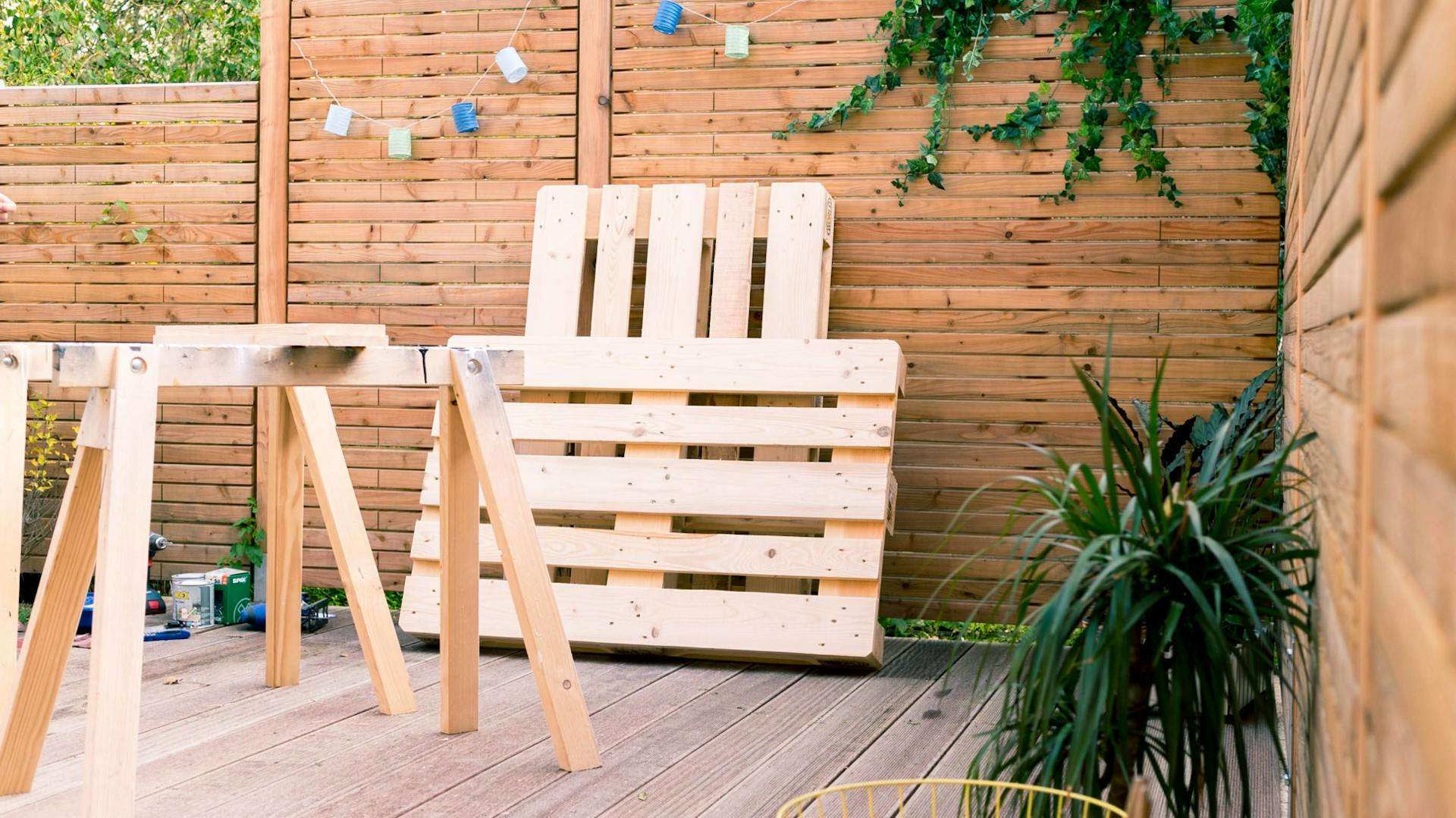 Paletten lehnend an Gartenzaun hinter Werkbock