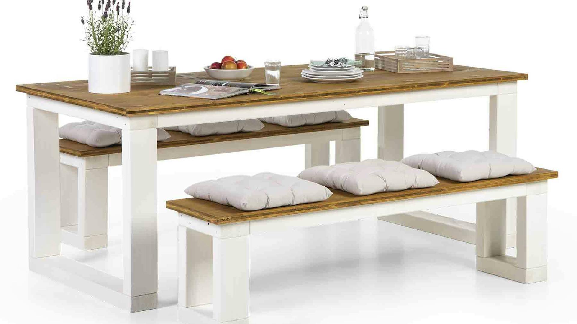 Tisch Karl mit Alltagsutensilien und zwei passenden Bänken mit weißen Kissen