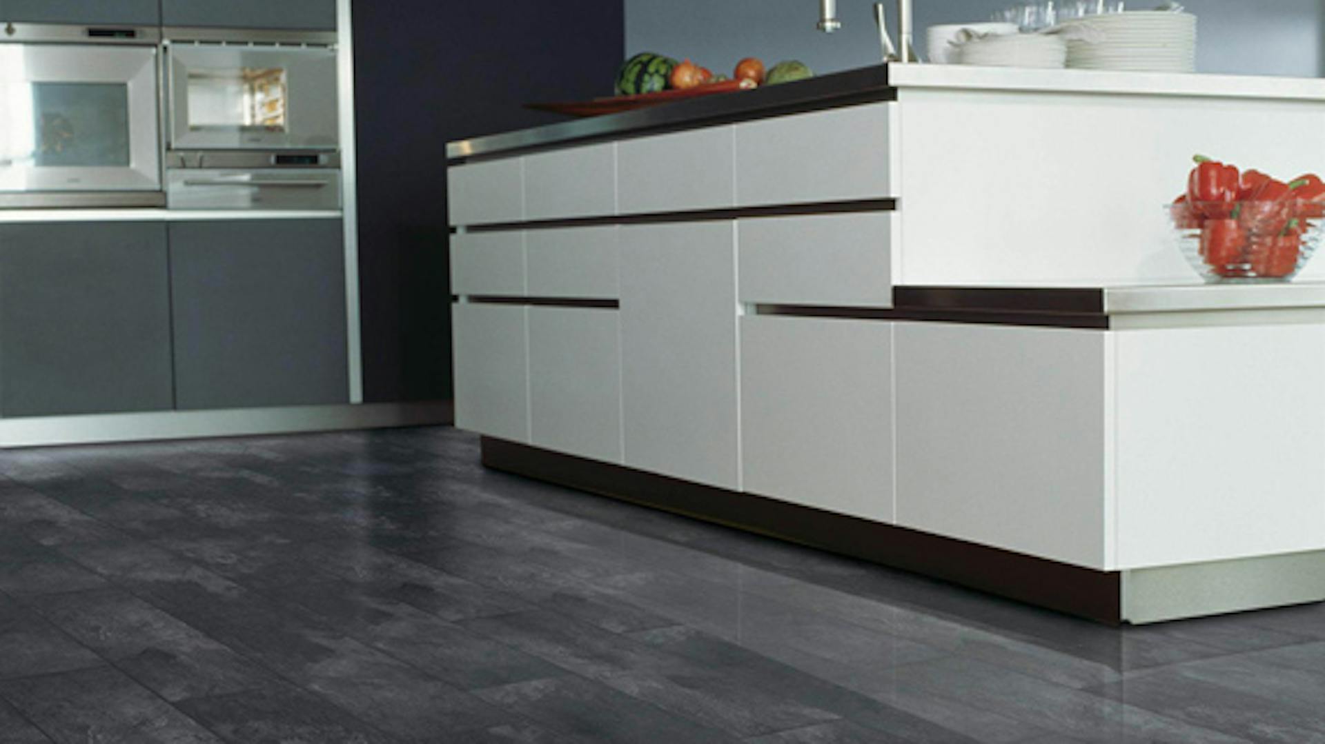 In schwarz-weißer Küche ist Laminat in Steinoptik verlegt.