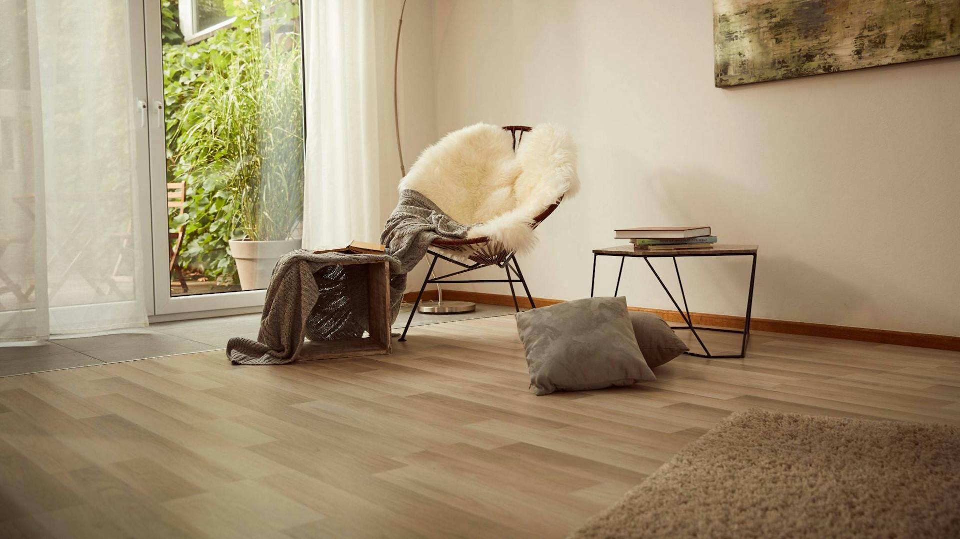 Im Wohnzimmer mit Laminatboden steht ein Stuhl mit zwei Beistelltischen, Kissen und Lampe.