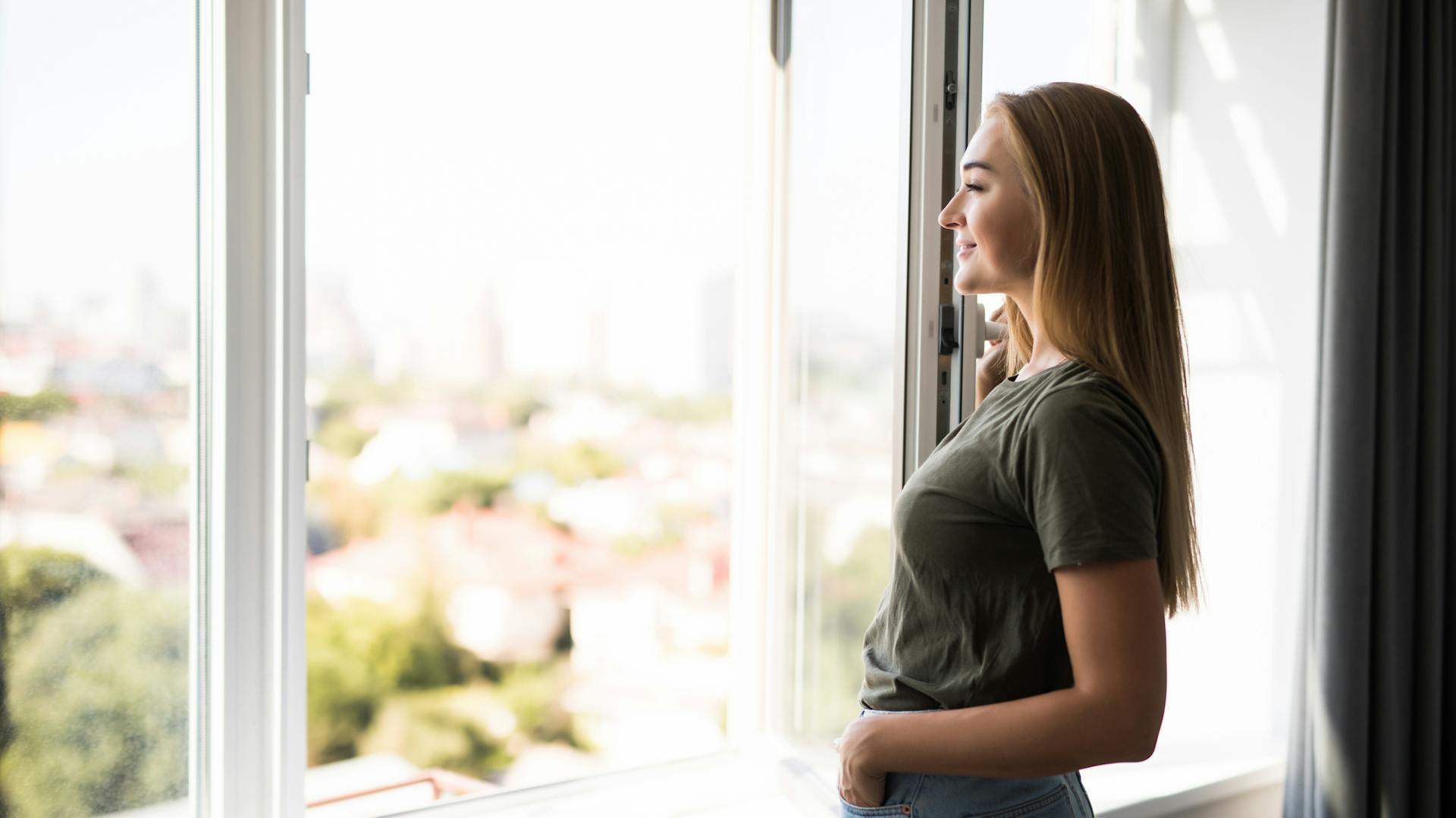 Eine Frau schaut aus einem geöffneten Fenster.