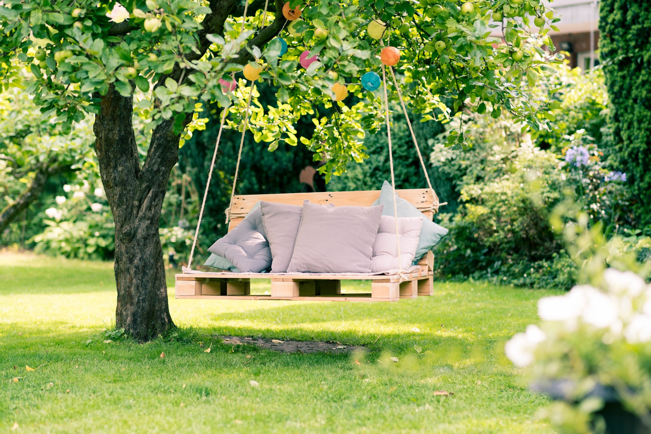 Da pallet e corde nasce un’altalena da giardino con cuscini.