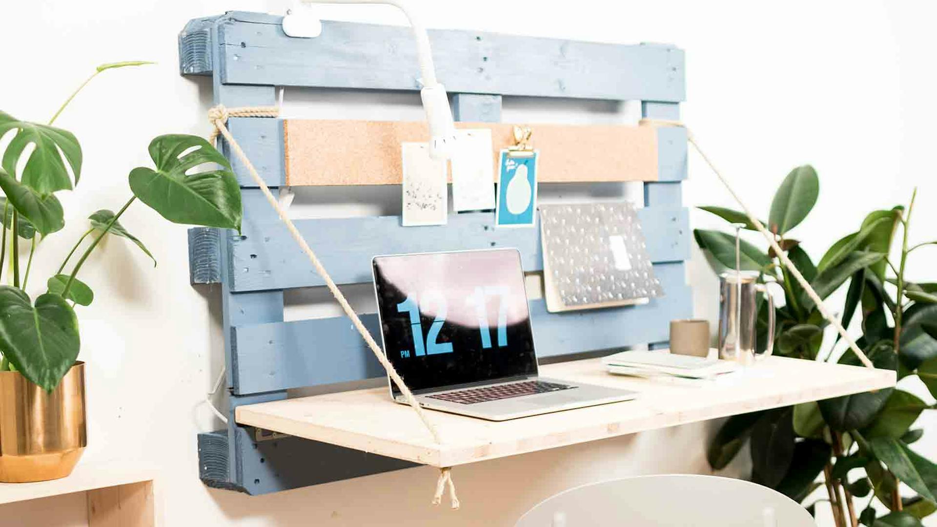 Un pallet montato a parete è fissato con un cordoncino a una tavola che funge da ripiano pieghevole.