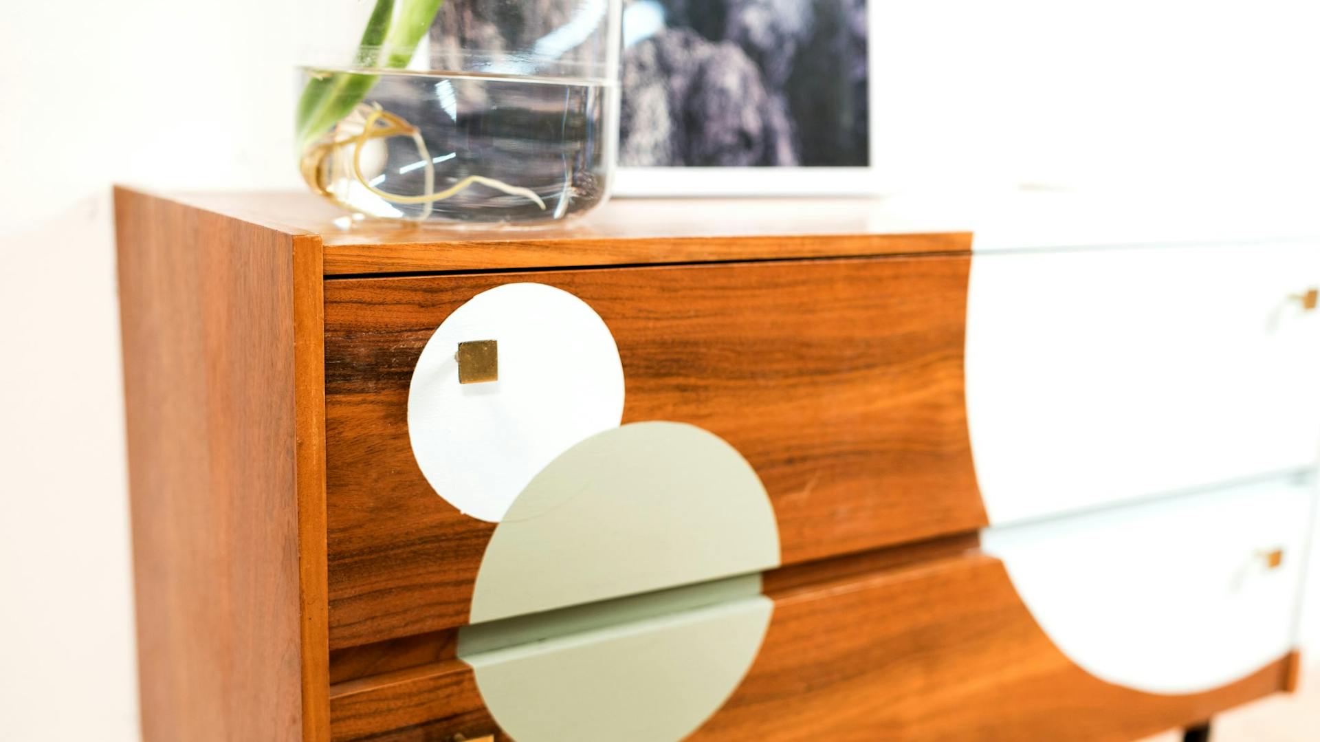 Světle hnědá komoda se zelenými a bílými barevnými kruhy.