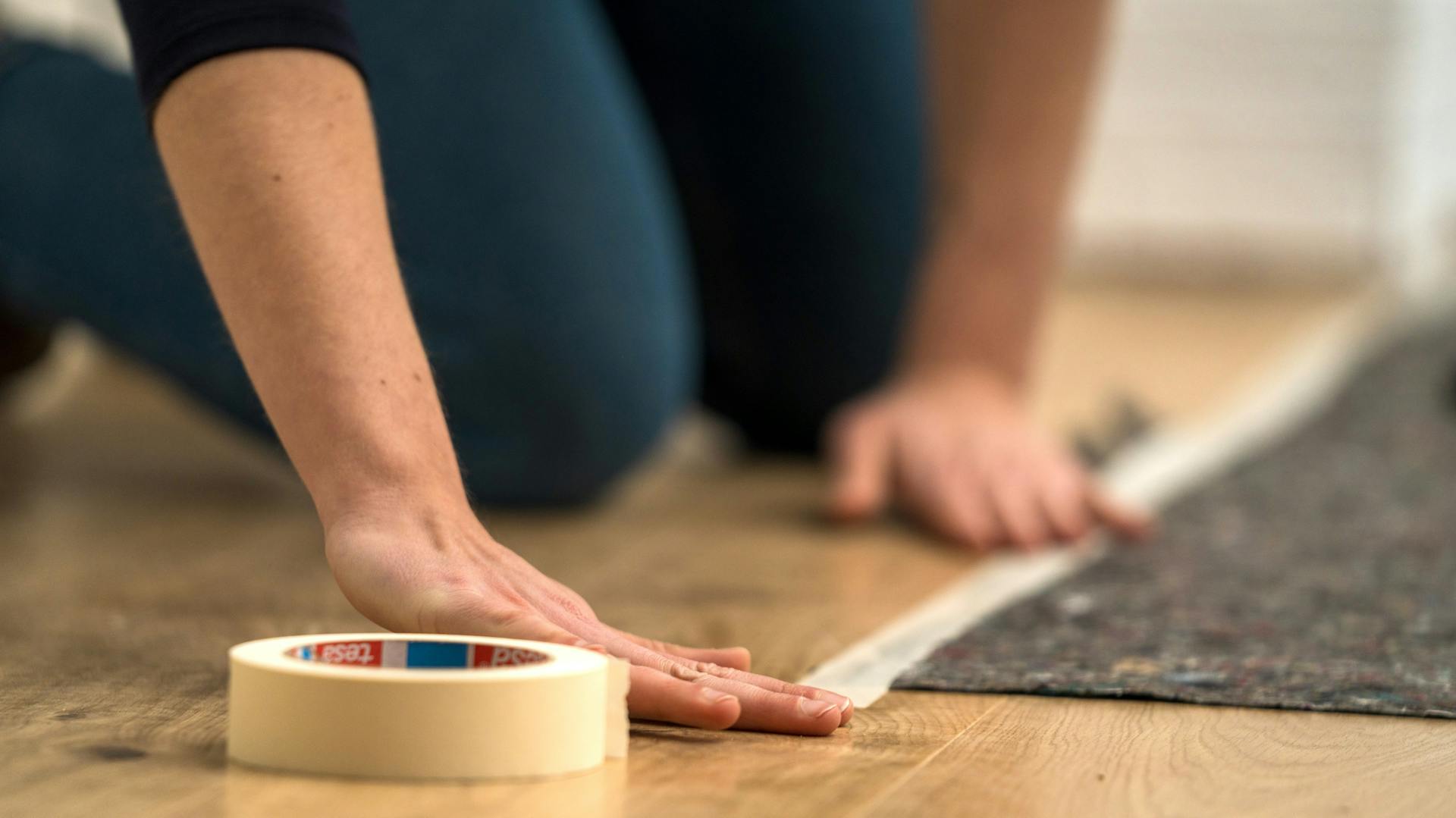 Person bedeckt den Boden mit Malervlies.