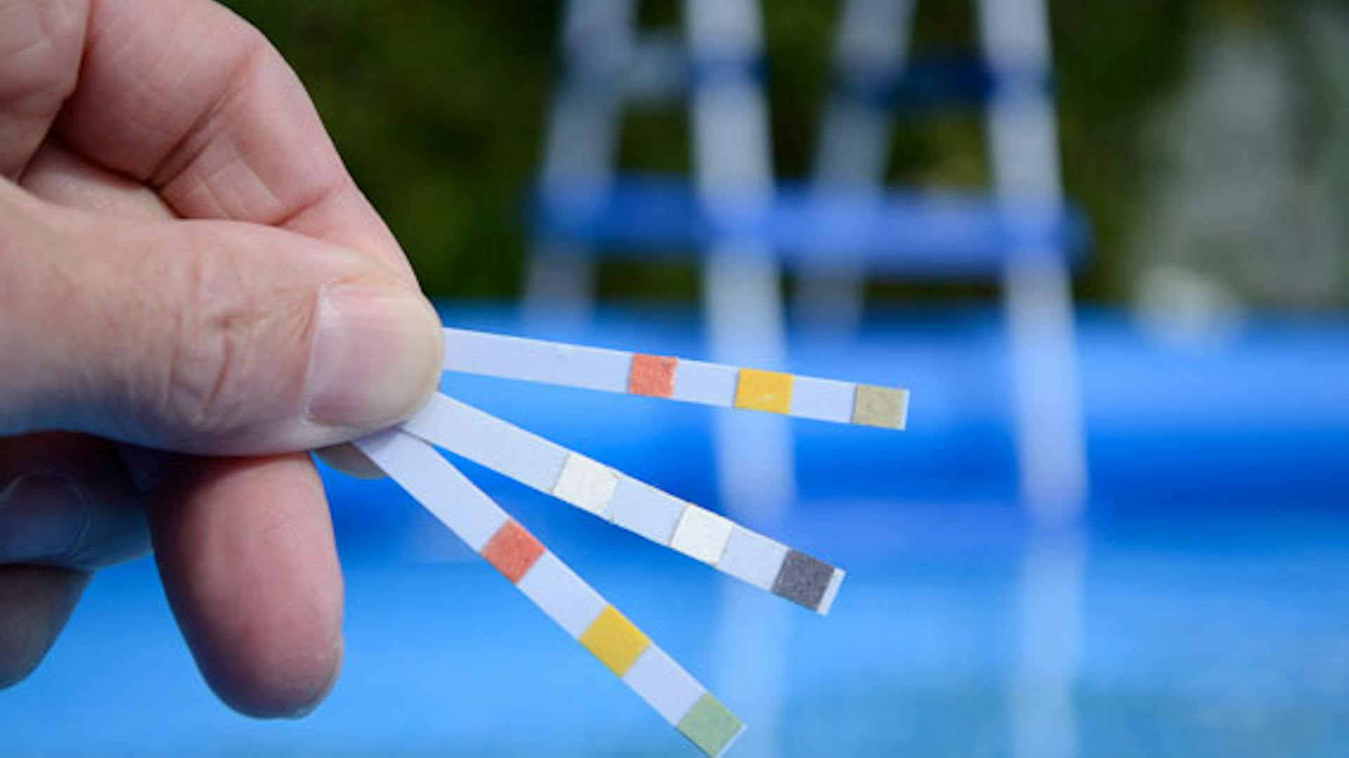 Valaki egy tesztcsíkot tart a kezében a pH-érték meghatározásához.