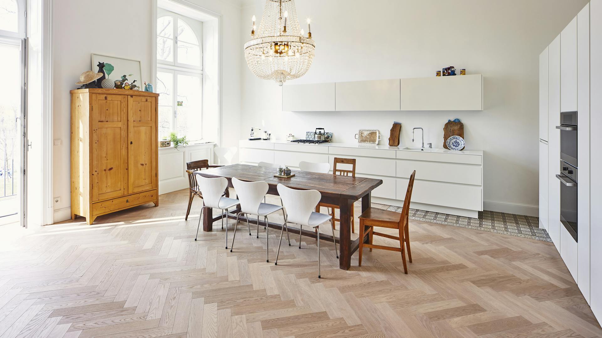 Großer Raum mit Küchenzeile, Esstisch, Hängelampe, Küchenschränke und Holzboden