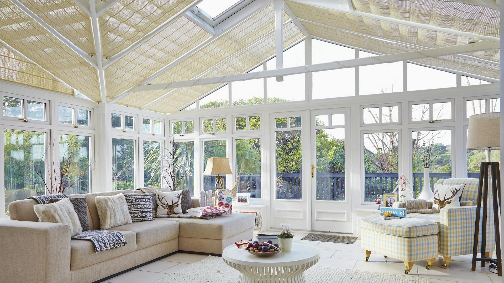 Geräumiger Wintergarten mit Loungemöbeln und heller Fensterfront.