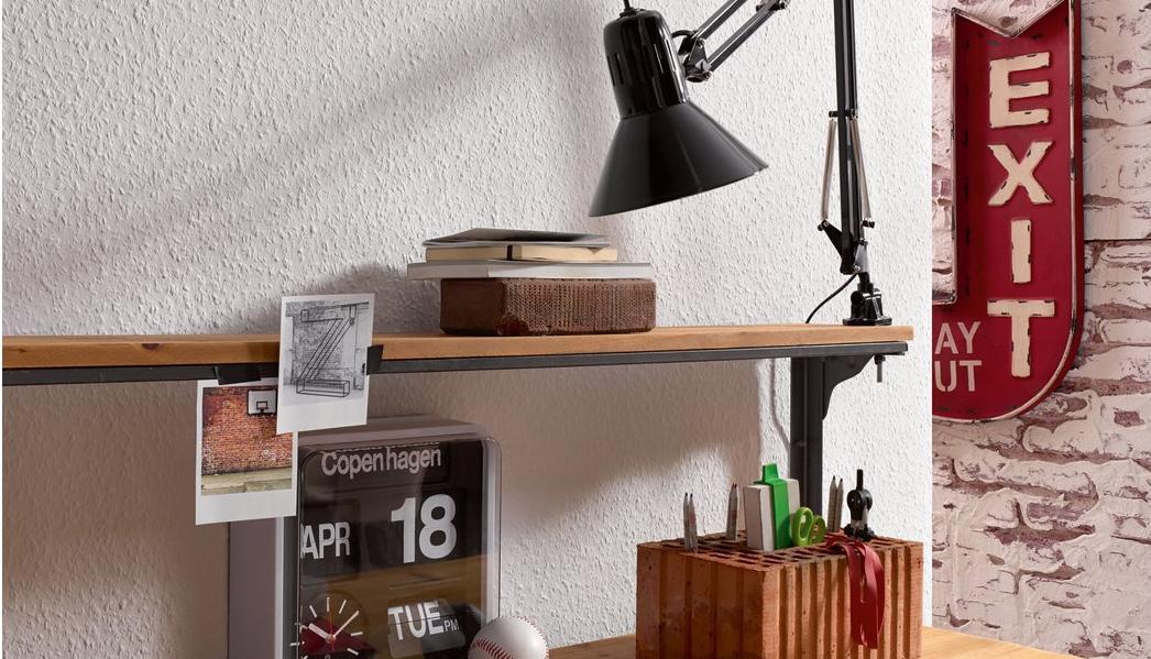 Ein Schreibtisch steht an einer mit Raufaser tapezierten, weißen Wand.