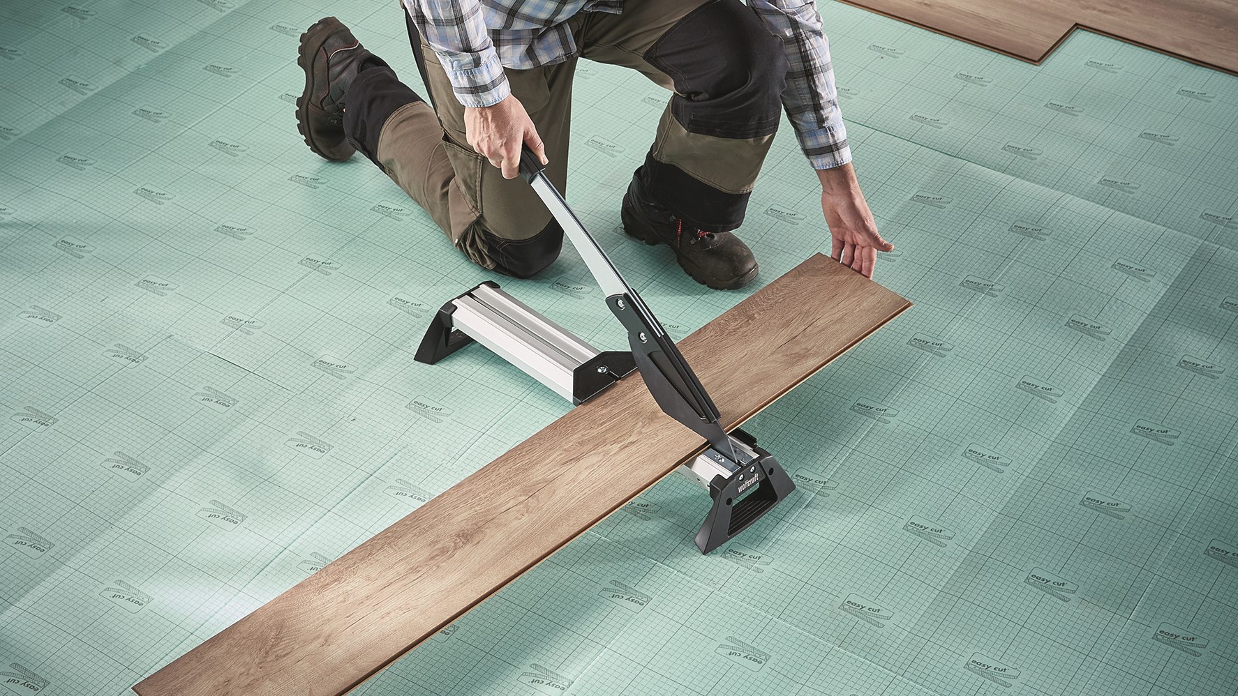 Eine Vinyl-Diele wird vom Heimwerker zugeschnitten.