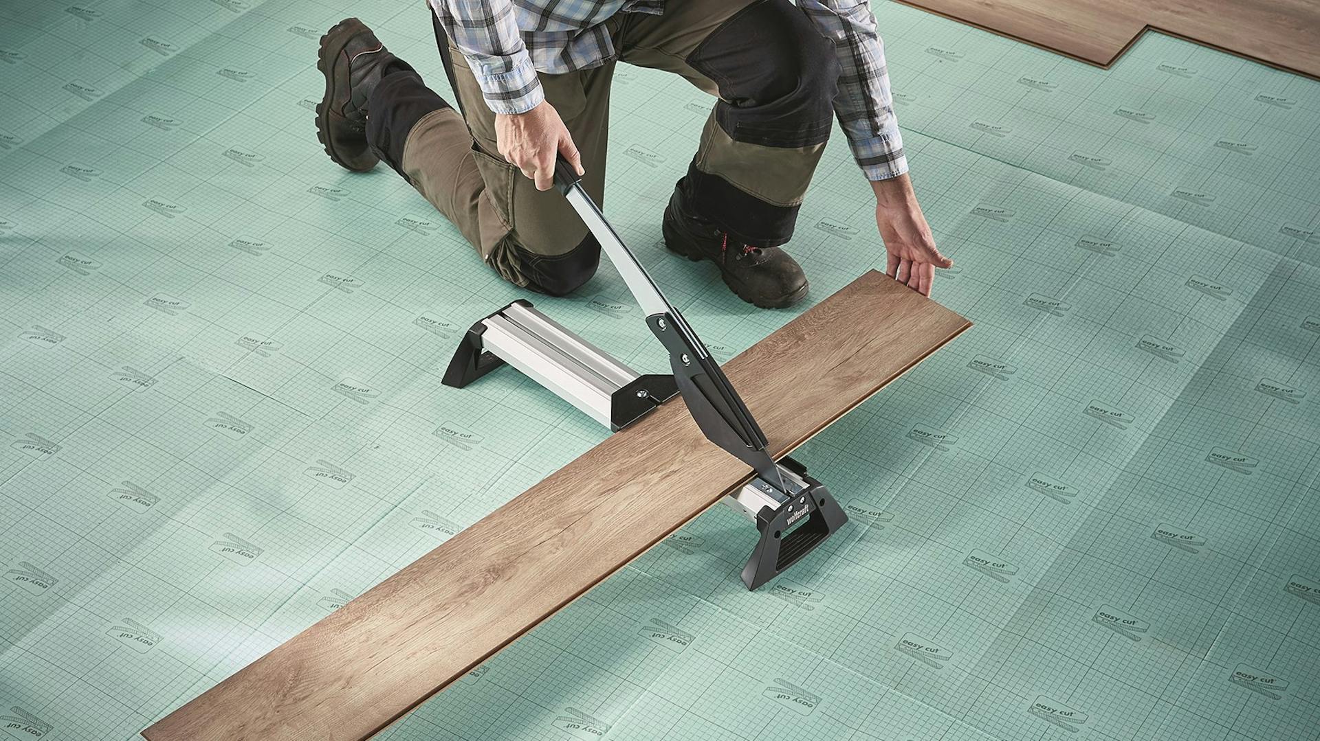 Eine Vinyl-Diele wird vom Heimwerker zugeschnitten.