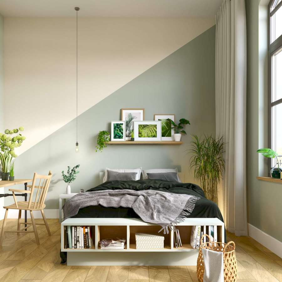 Ein Bett steht vor eine Wand, die große geometrische Formen in dezenten Pastelltönen als Wandsgestaltung nutzt.