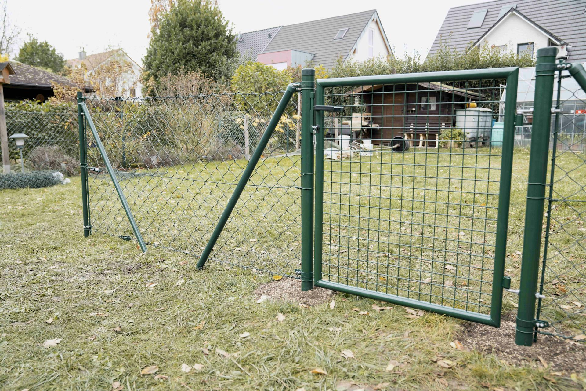 Grünes Gartentor mit einbetonierten Zaunpfosten