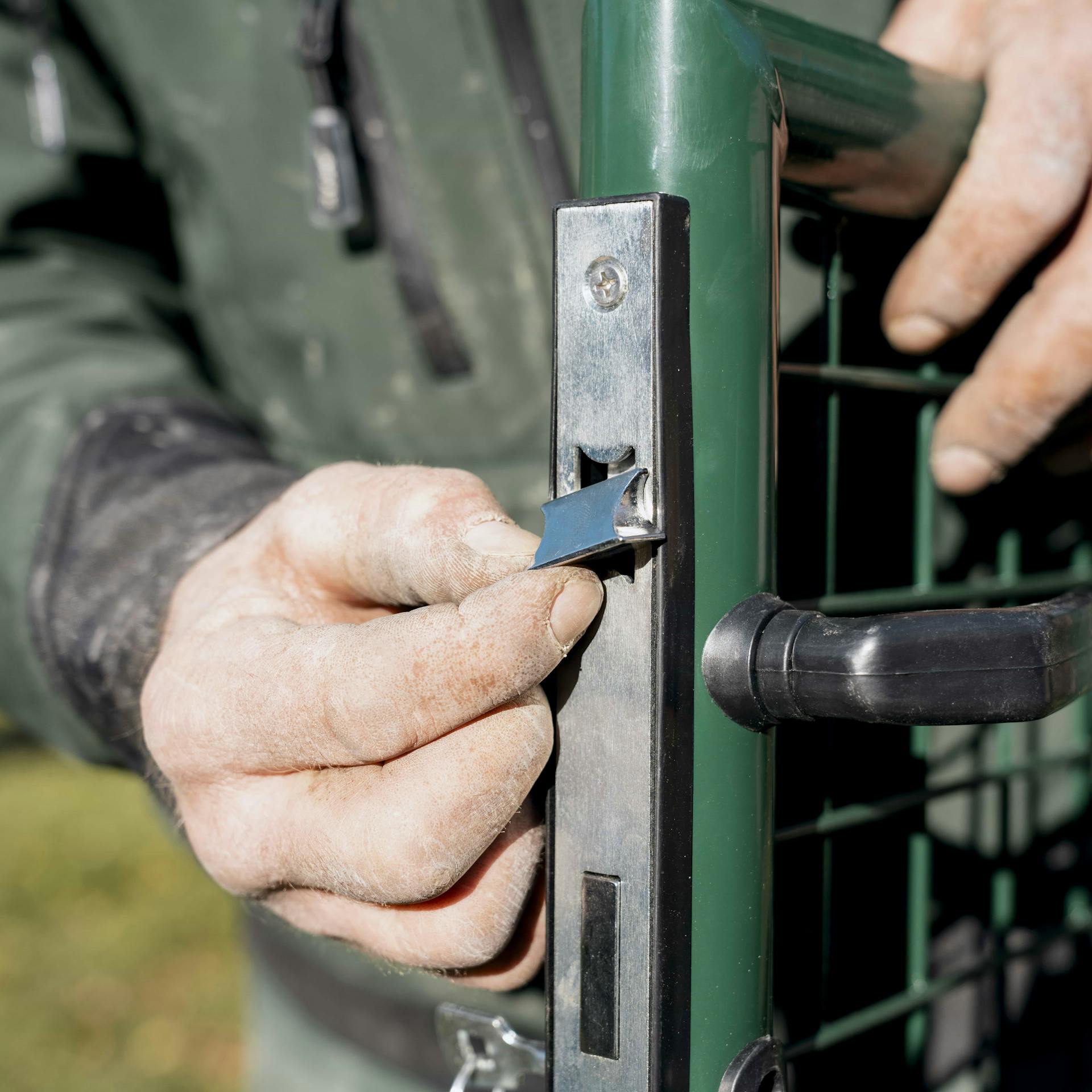 Heimwerker dreht am Schließblech des Gartentores.