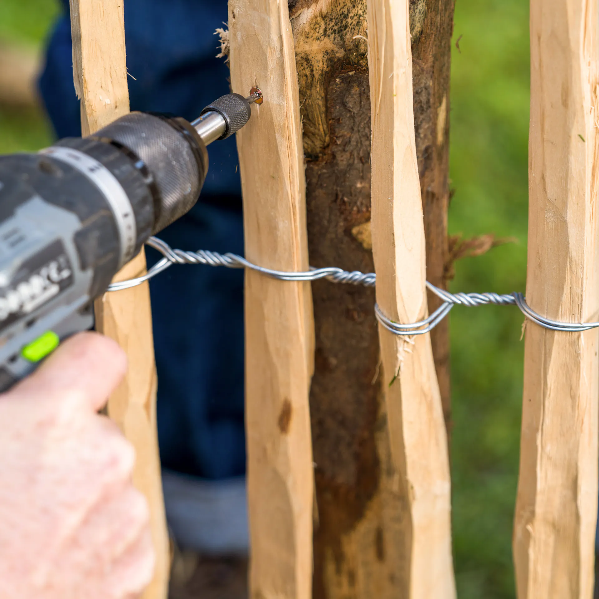 Staketenzaun wird an Holzpfahl geschraubt