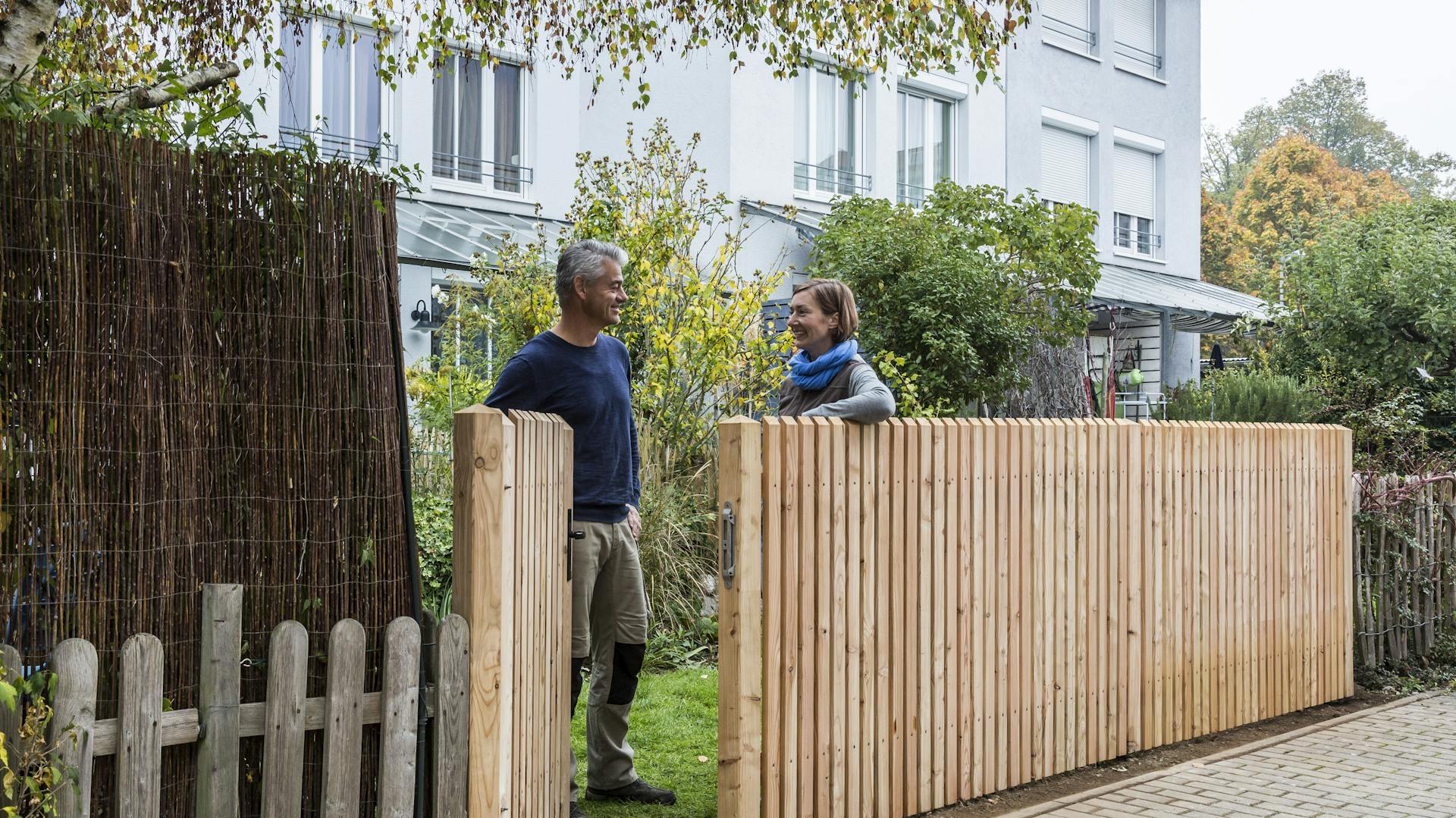 Kerítésépítés házilag: Egy férfi és egy nő áll az új kerítésnél.