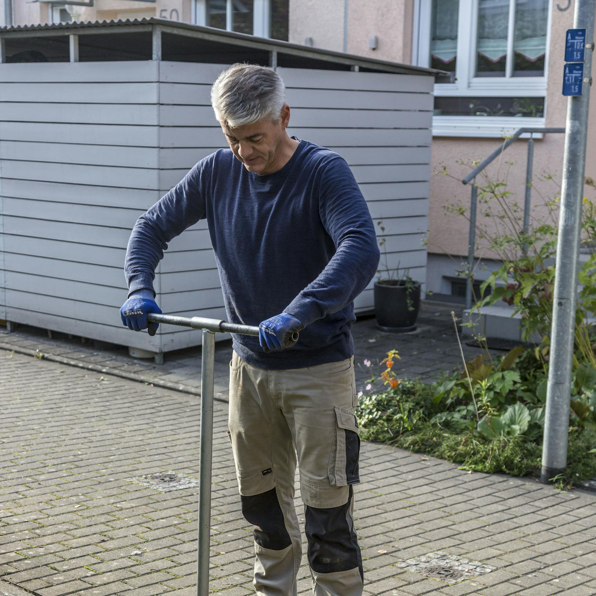 Ein Mann bohrt mit einem Erdbohrer ein Loch für ein Fundament.