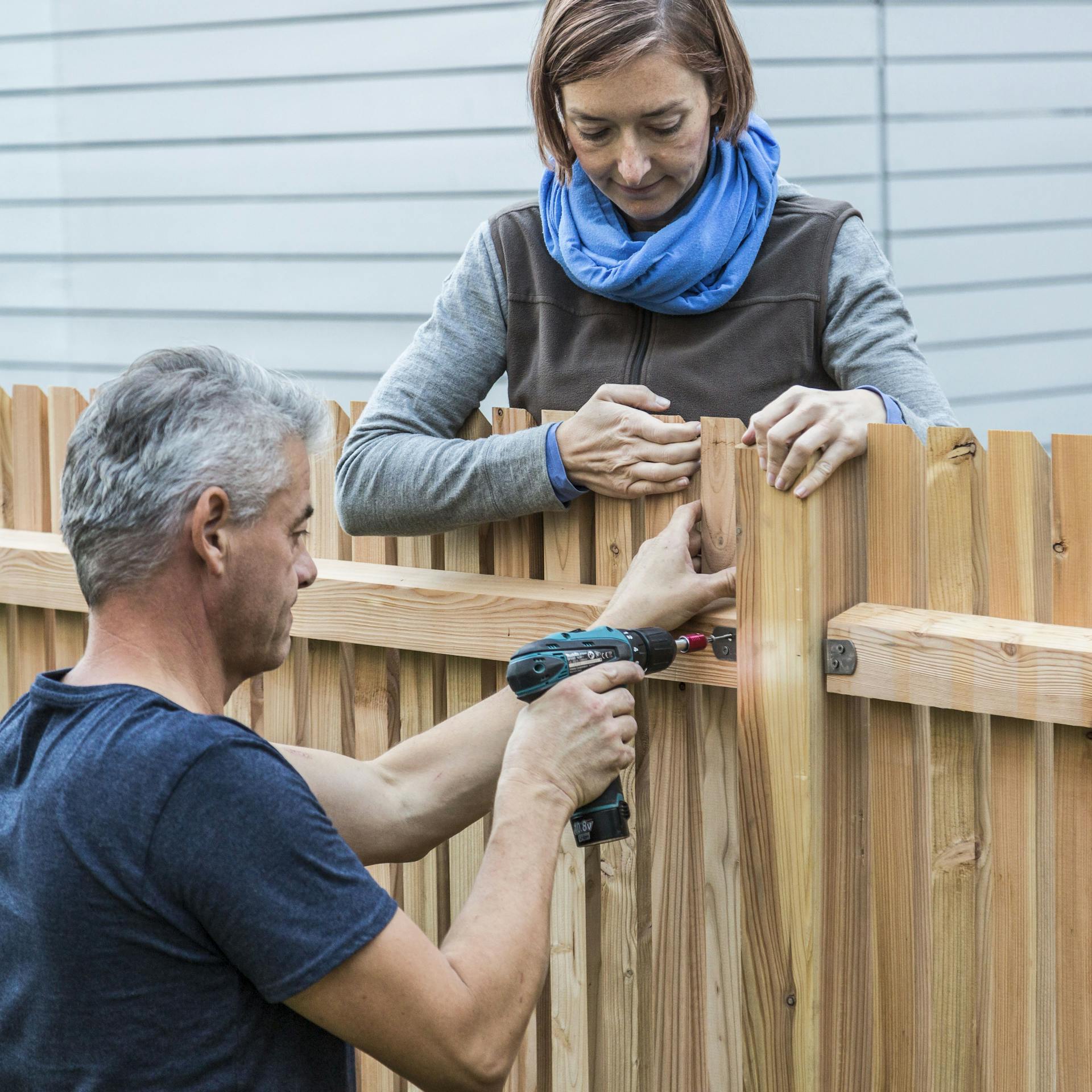 Zwei Personen montieren Zaunelemente.