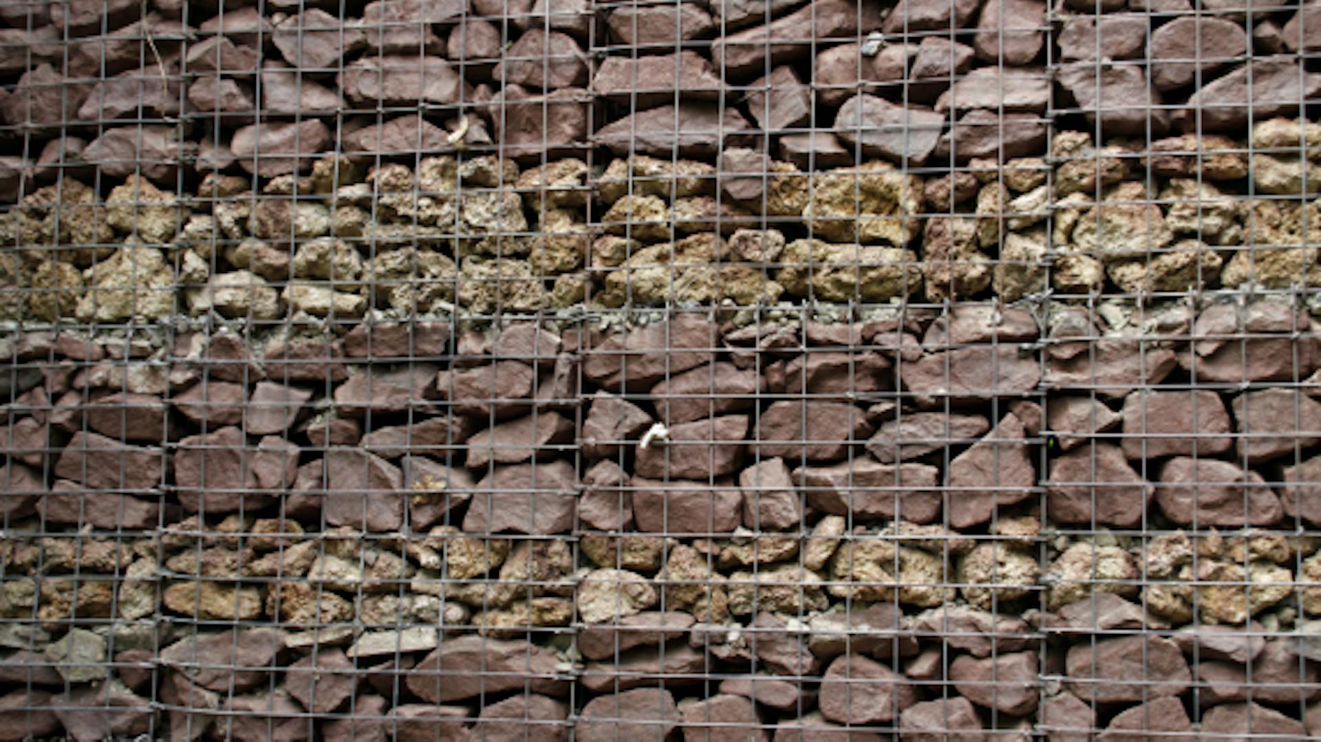 Primo piano di un gabbione con pietre come protezione fendivista.