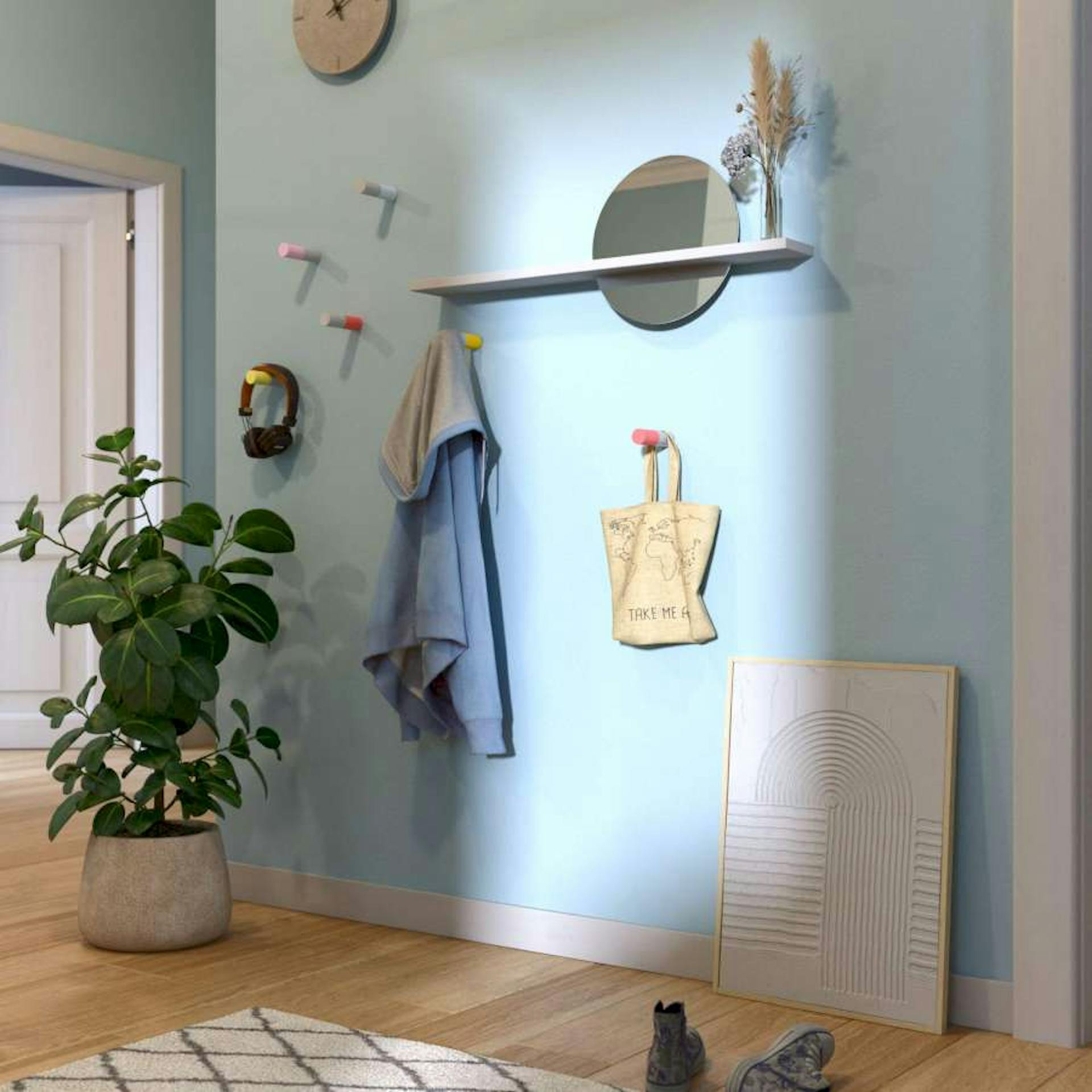 In einem hellblauen Flur wurden DIY-Wandhaken und ein Spiegel angebracht. Vor der Wand stehen eine Bild und eine Pflanze.