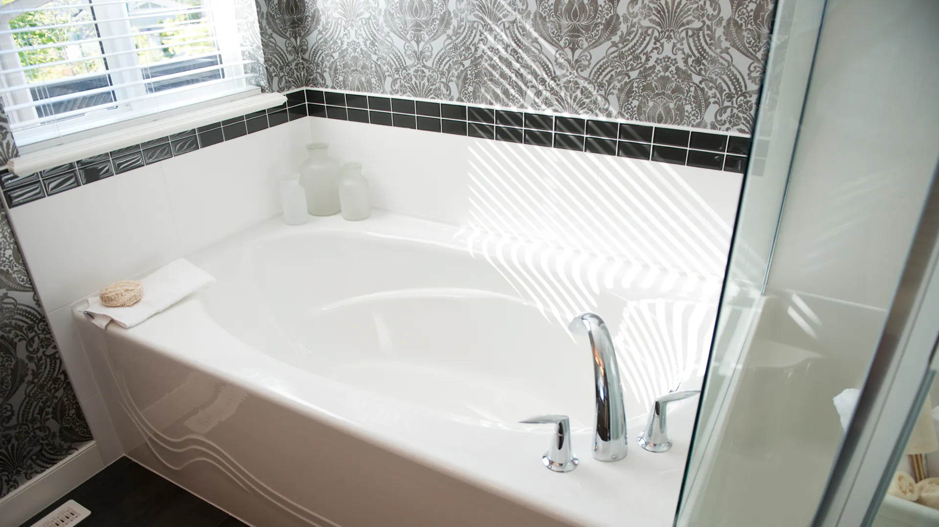 Weiße Badewanne vor dunkel gemusterter Tapete