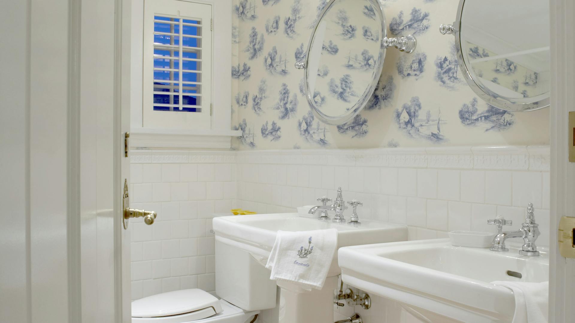 Blau-weiße Blumentapete in einem Badezimmer mit weißer Ausstattung.