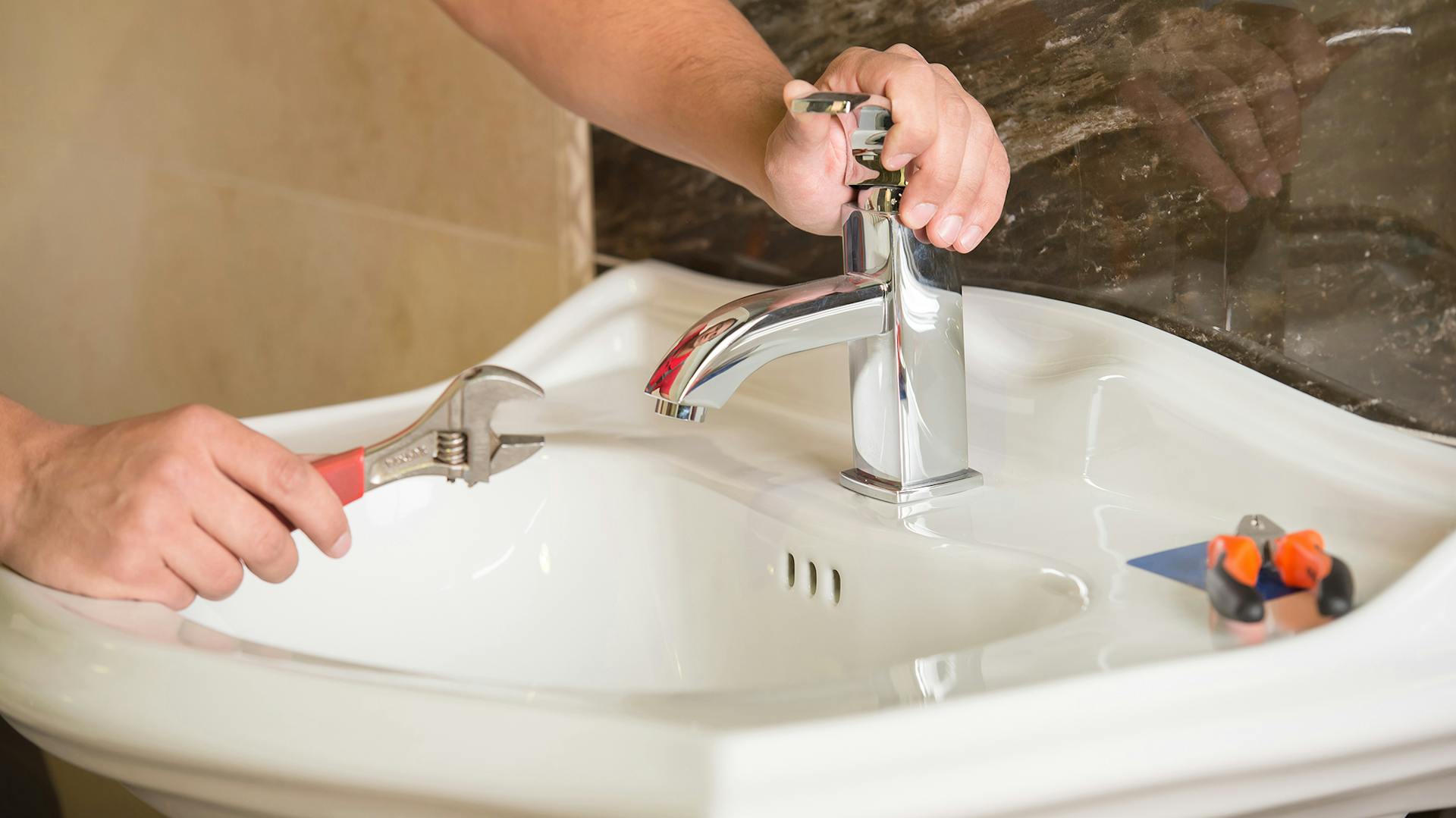 A személy csatlakoztatja a vízcsapot a mosdókagylóhoz.