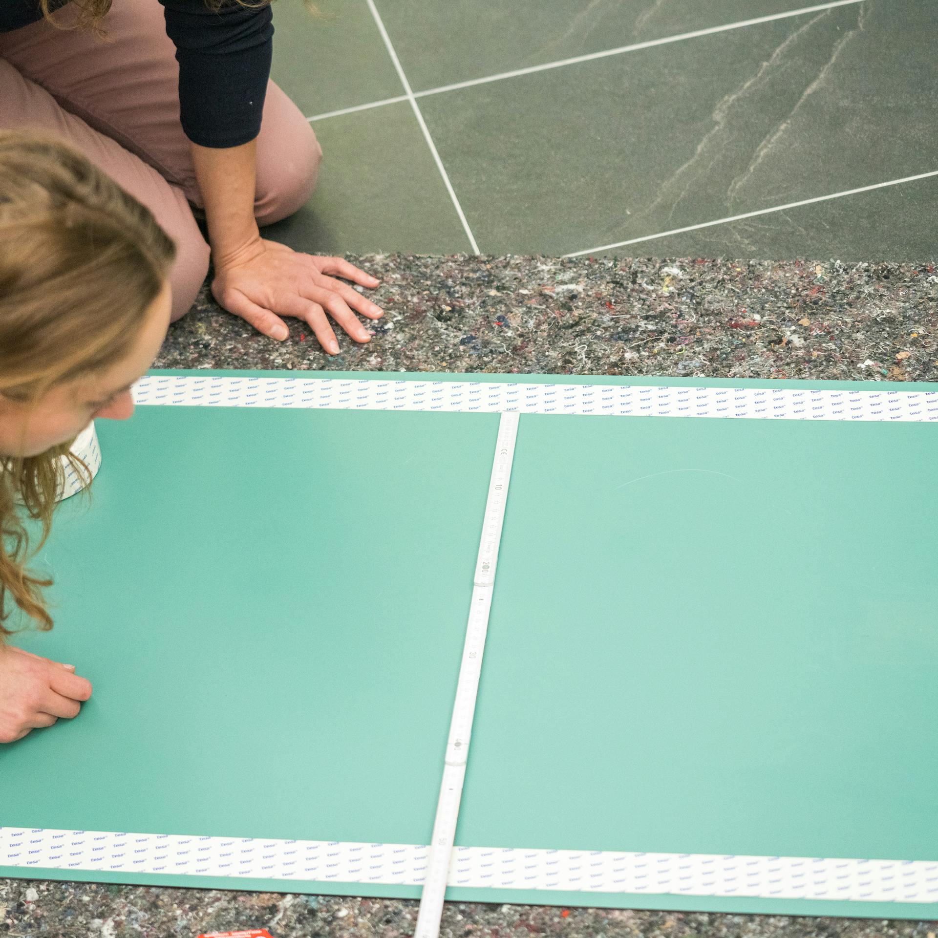 Handwerker bringen doppelseitiges Klebeband auf der Rückseite eines Spiegels an.