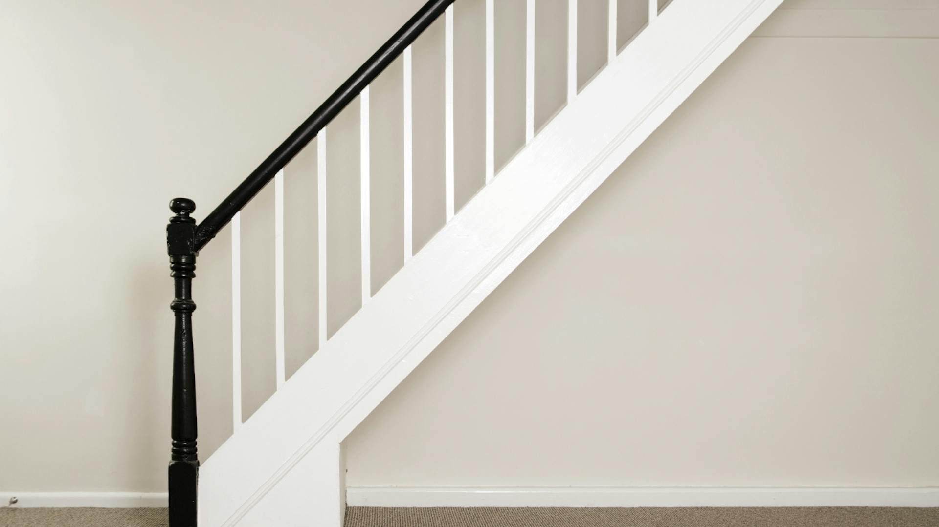 Weiß lackierte Treppe mit schwarz lackiertem Geländer.