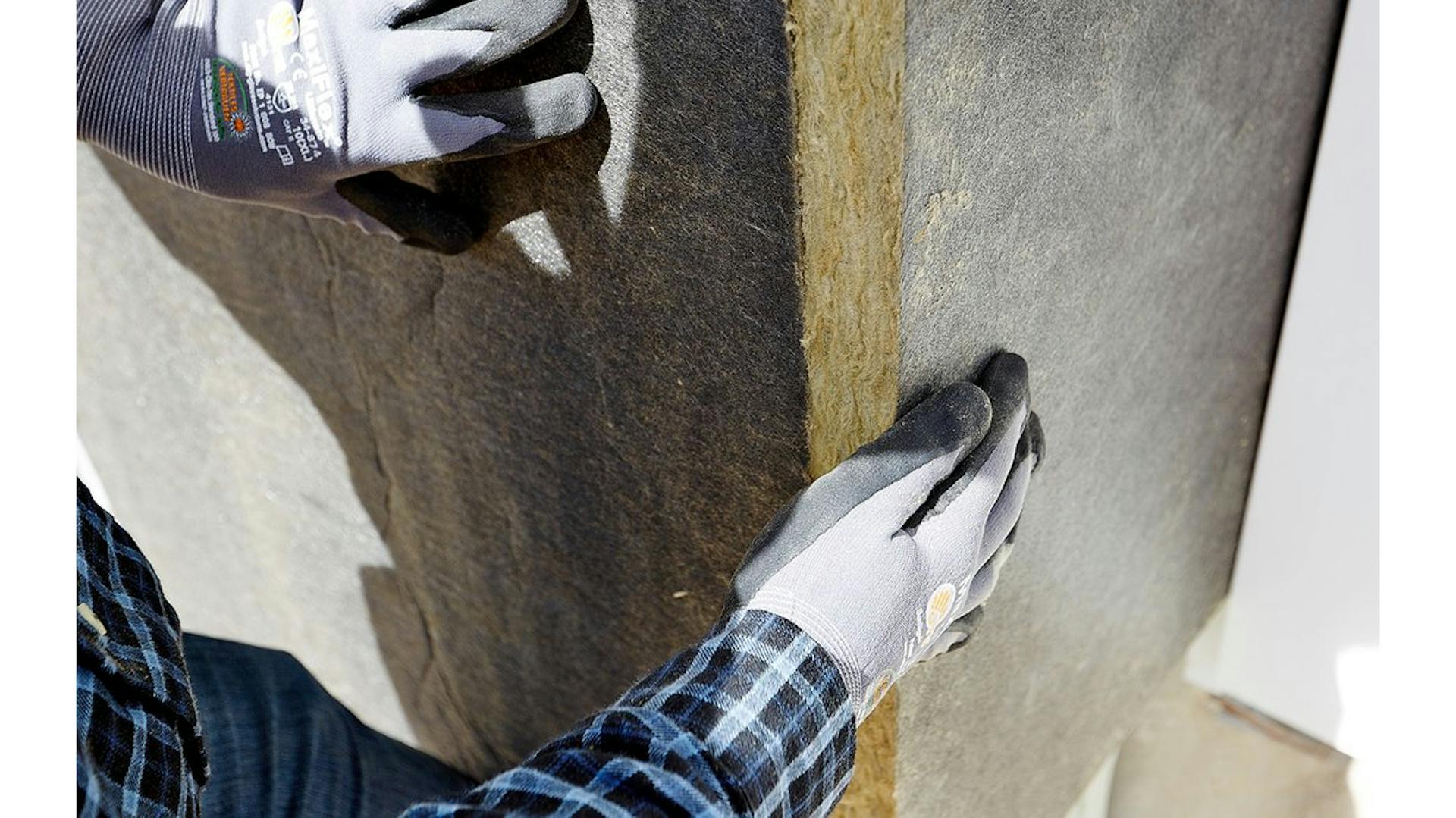 Nahaufnahme von zwei Händen, die Matten aus Steinwolle befestigen.