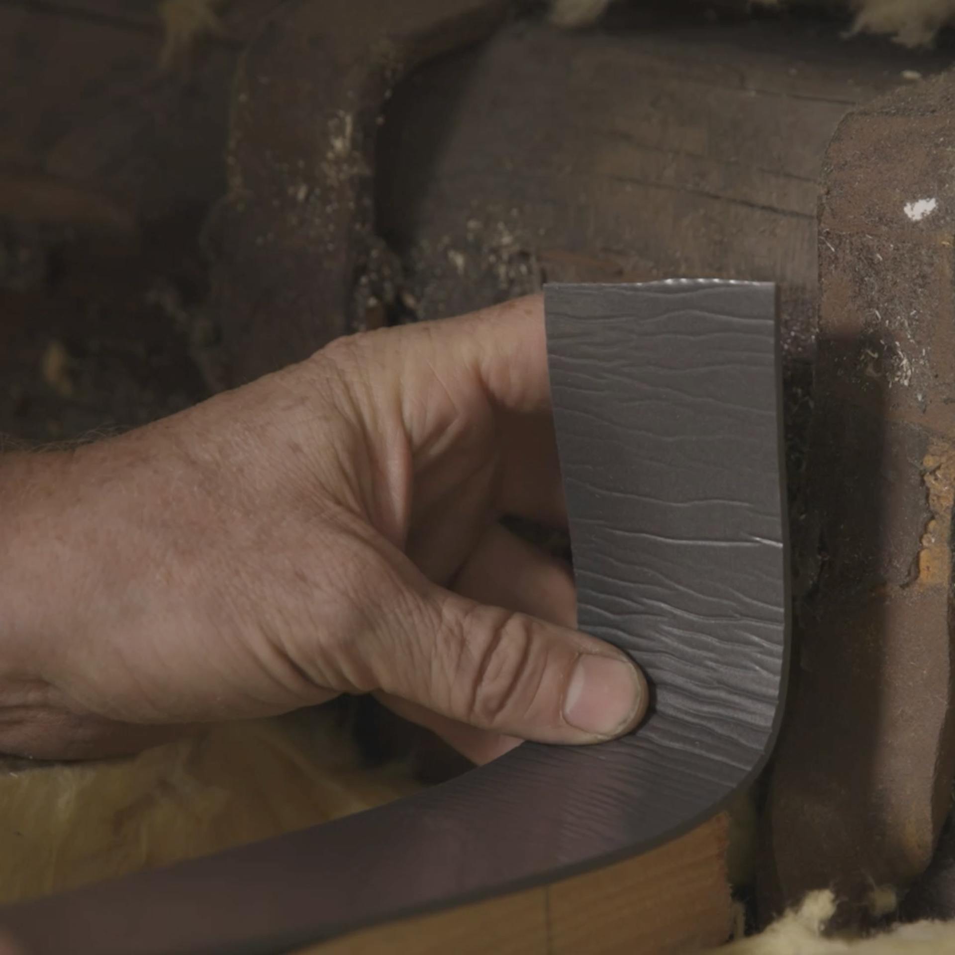 Entkopplungsband wird von Handwerker auf Bohle aufgeklebt.